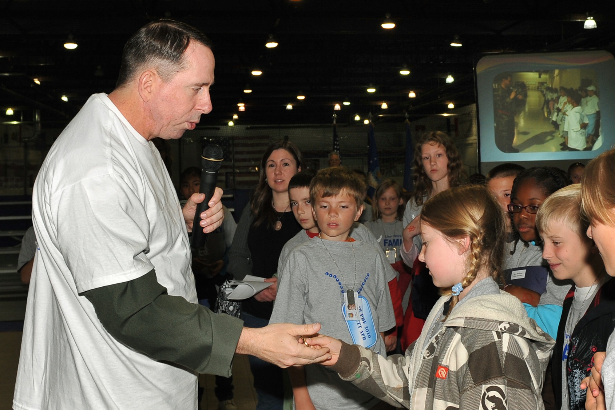 OFFUTT AIR FORCE BASE, Neb. -- Brig. Gen. John N.T. Shanahan, 55th wing commander, gives a commander's coin to a child after she guessed how many people from the Fightin' Fifty-Fifth were deployed during the Junior PDF Line at the Offutt Field House May 7.  More than 260 children participated in the event to gain a better understanding of what their parents experience when they deploy. U.S. Air Force Photo by Charles Haymond