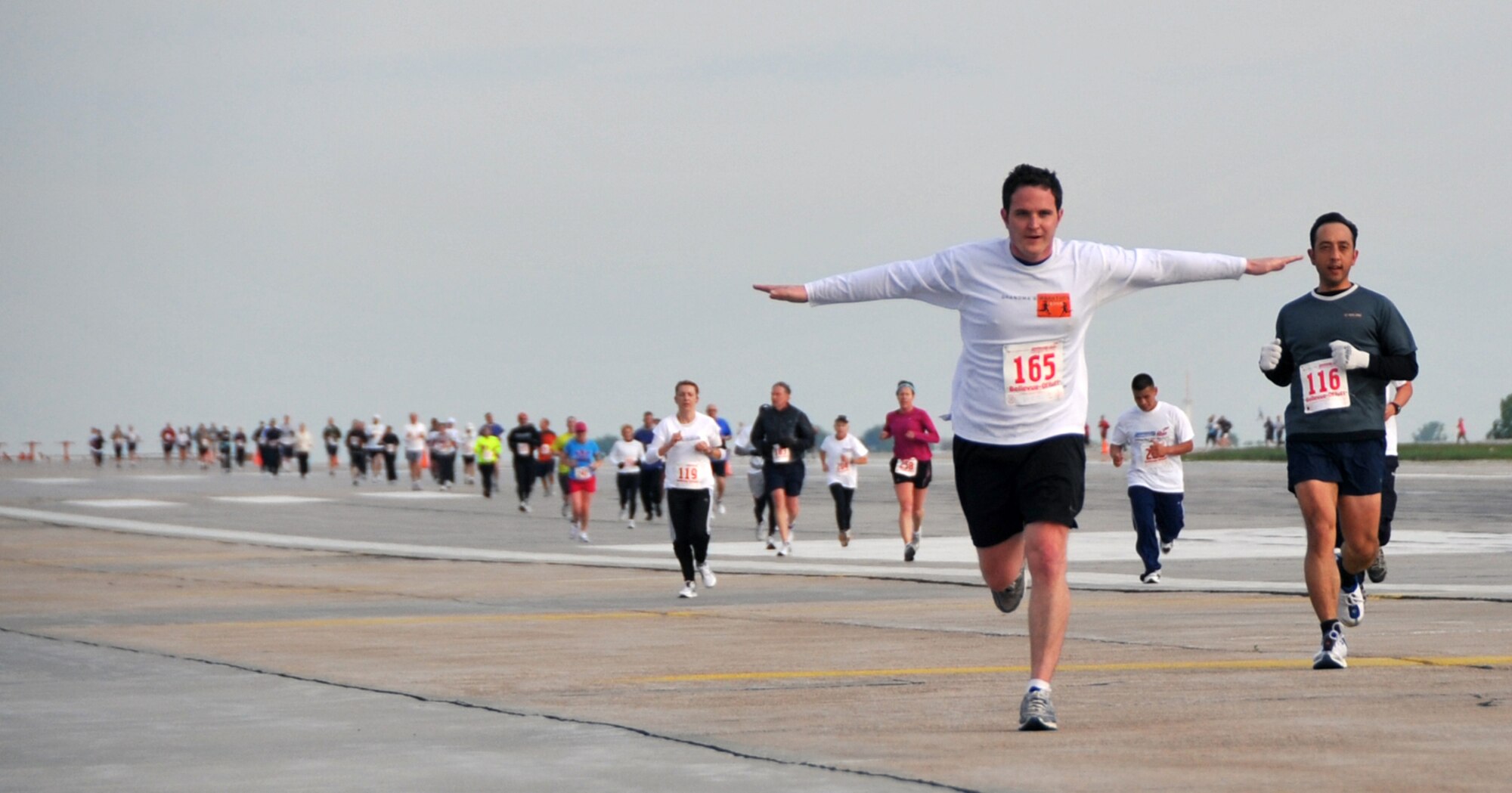 OFFUTT AIR FORCE BASE, Neb. -- Robert Harris, of Omaha, gives his best impression of a flying aircraft while running on the flightline here during the third annual Runway Run May 9. The seven mile race started at the Bellevue Welcome Center in Bellevue, Neb., and included about two miles of Offutt's runway. U.S. Air Force Photo by Jeff W. Gates