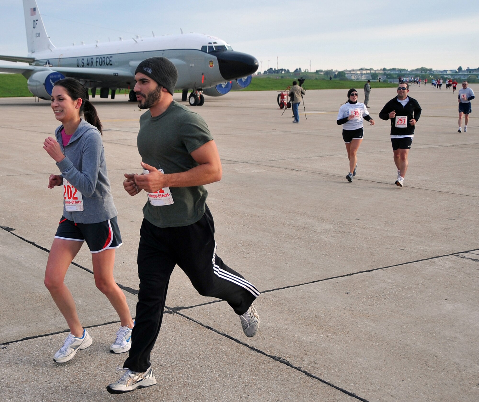 OFFUTT AIR FORCE BASE, Neb. -- Stephanie McLaughlin and Jeremy Carini from Bellevue, Neb., run past an RC-135 Rivet Joint aircraft here May 9 during the third annual Bellevue-Offutt Runway Run.The seven mile race, which started at the Bellevue Welcome Center, included about two miles of Offutt's runway. U.S. Air Force Photo by Jeff W. Gates
