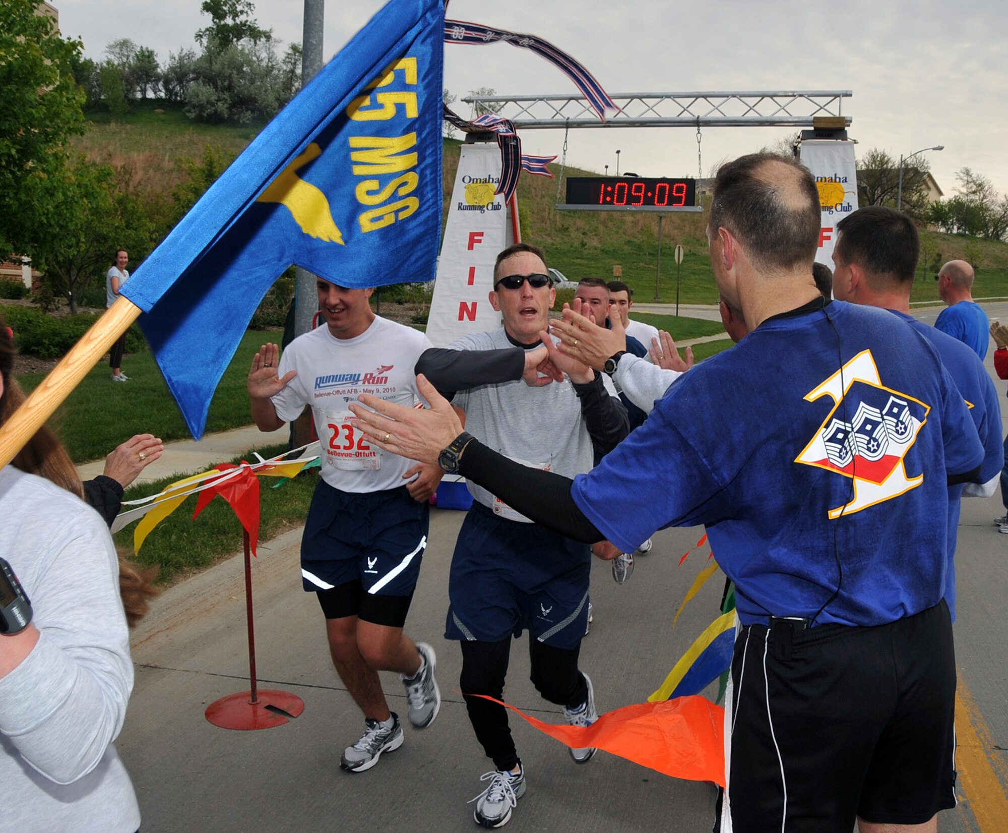OFFUTT AIR FORCE BASE, Neb. -- Members of the 55th Mission Support Group are greeted by several high fives as they finish the third annual Bellevue-Offutt Runway Run May 9. More than 140 runners participated in the seven mile race which included about two miles on Offutt's runway. U.S. Air Force Photo by Jeff W. Gates