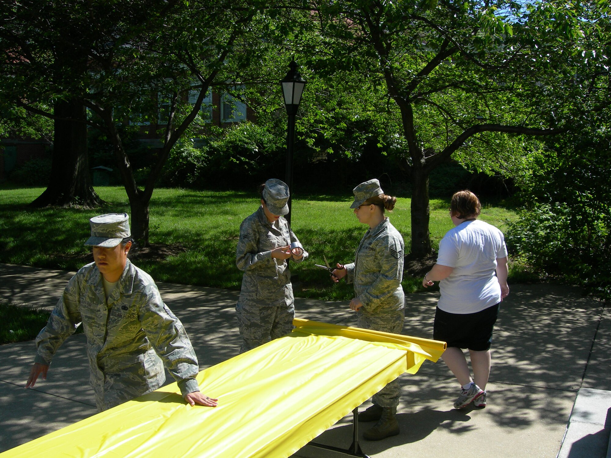 Air Force District of Washington volunteers Master Sgt. Rica Taylor, NCOIC Knowledge Operator, Airman 1st Class Mary Fifer, Personnel Specialist and Staff Sgt. Stacey Barker, NCOIC Command and Control assists Ms. Amanda Jensema, Armed Force Retirement Home, Recreation Therapist prepare tables for May Spring Cookout for the residents at the Armed Forces Retire Home Washington, D.C., held on May 7, 2010. (U.S. photo by Aletha Frost)