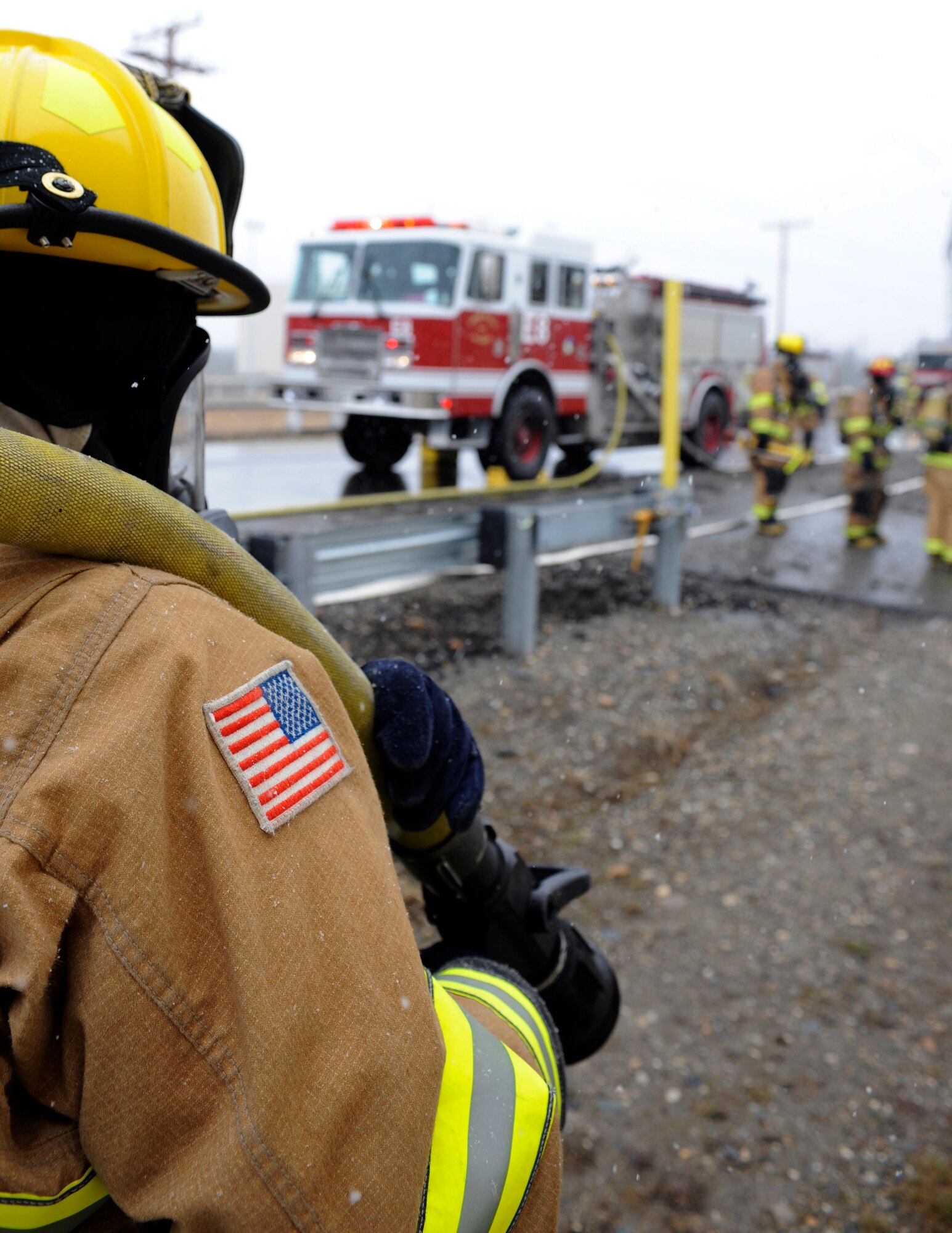 A firefighter pulls a fire hose to a simulated fire May 5, 2010, Eielson Air Force Base, Alaska. Emergency service Airmen responded to a mock aircraft crash at the fuel storage field during the May operational readiness exercise. The firefighter is a part of the 354th Civil Engineer Squadron, Fire Protection Flight. (U.S. Air Force photo/Airman 1st Class Willard E. Grande II)
