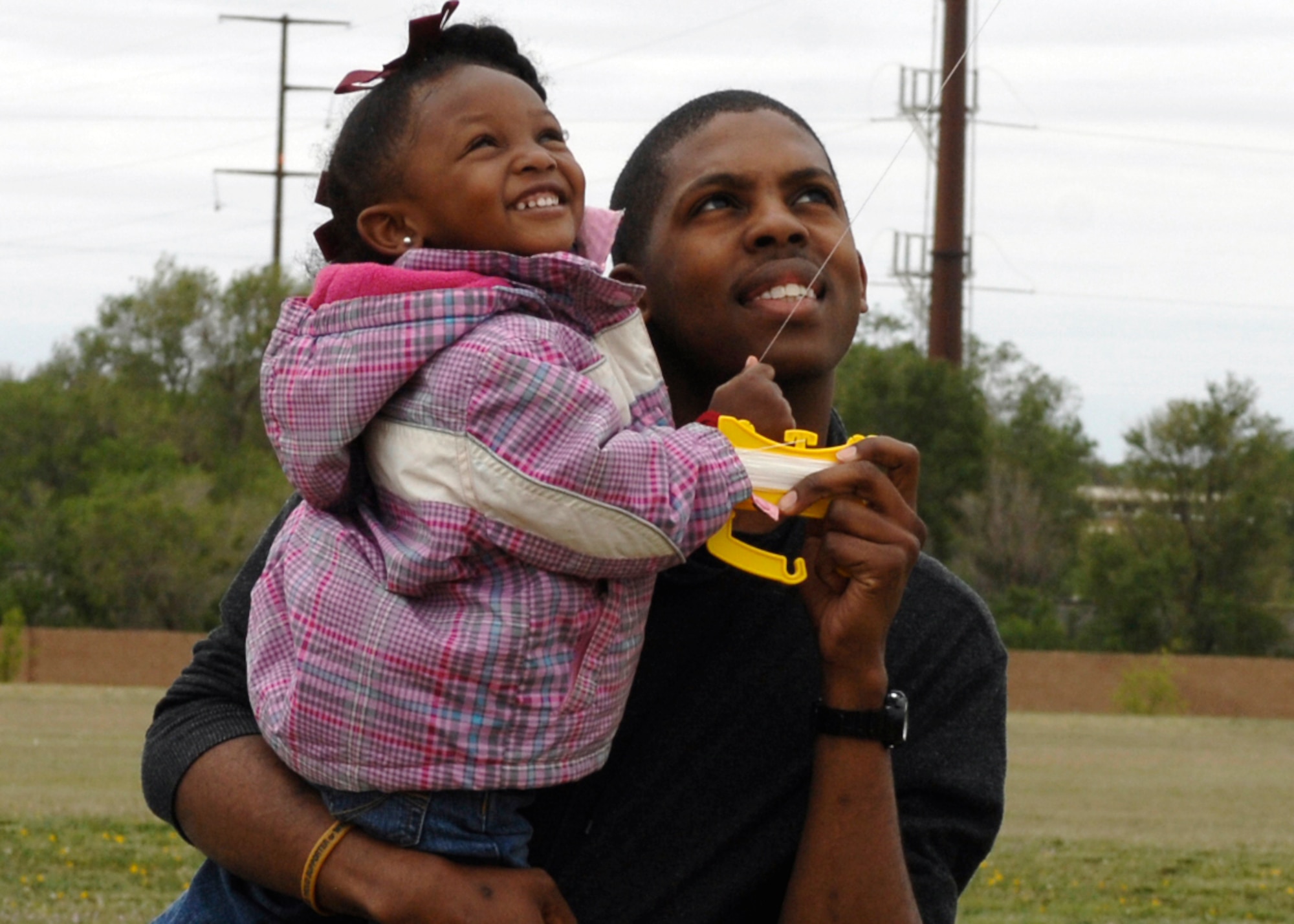 Senior Airman Joshua Goins, 27th Special Operations Component Maintenance Squadron, holds the string as his daughter Jaidyn guides their kite during the Cannon Air Force, Base, N.M.,  seventh-annual Kite Karnival on May 8. An estimated 400 kite enthusiasts turned out for the event at Doc Stewart Park. (Air Force photo by Greg Allen) 
