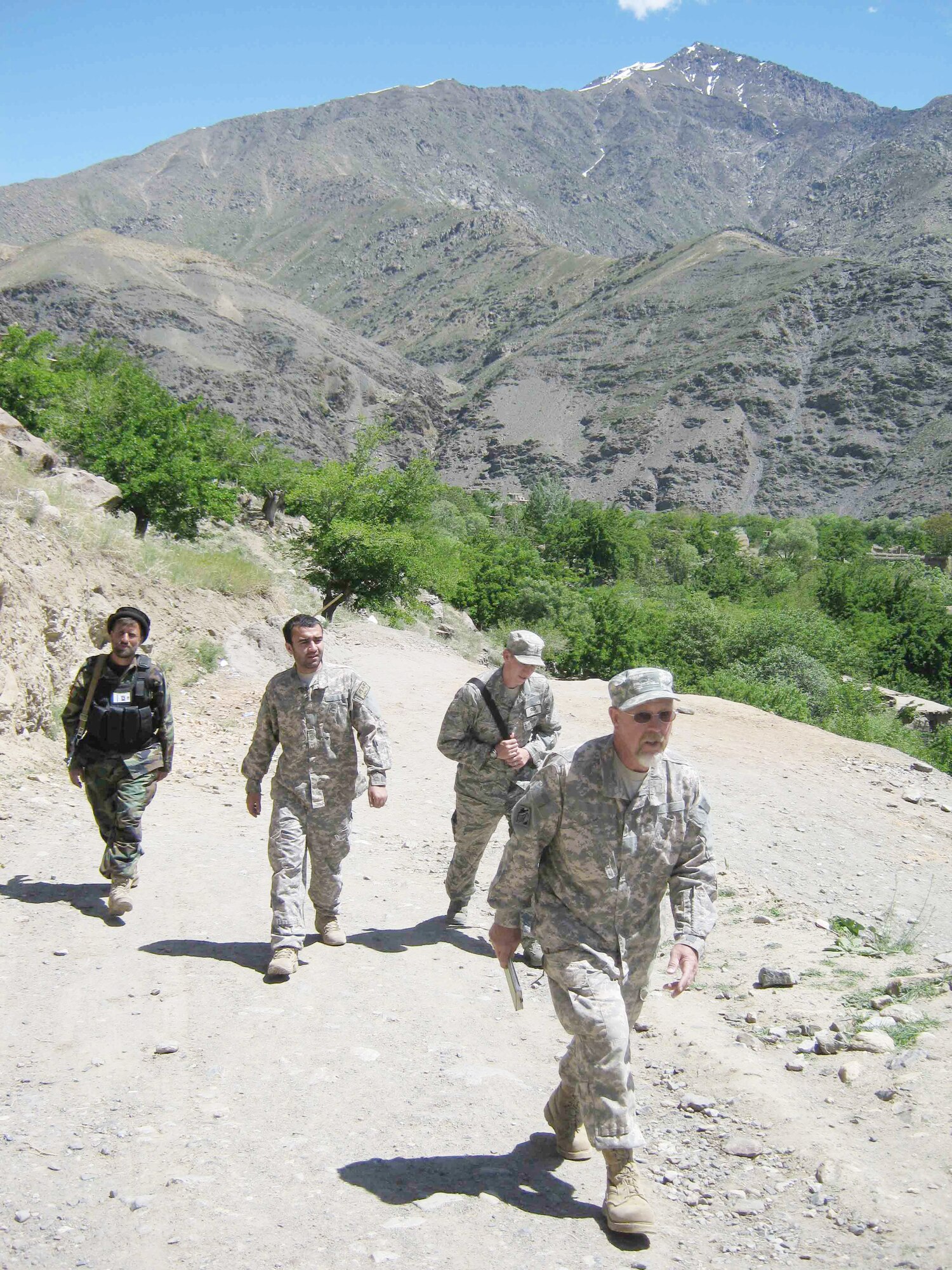 Scott Davis (front) and 2nd Lt. Jason Adams (back, right) walk with an interpreter and local mujahedeen guard at Panjshir Province, Afghanistan. Mr. Davis is a construction representative for the Army Corps of Engineers attached to Provincial Reconstruction Team Panjshir. Lieutenant Adams is a PRT Panjshir civil engineer. (U.S. Air Force photo/2nd Lt. Jason Smith, PRT Panjshir Public Affairs)