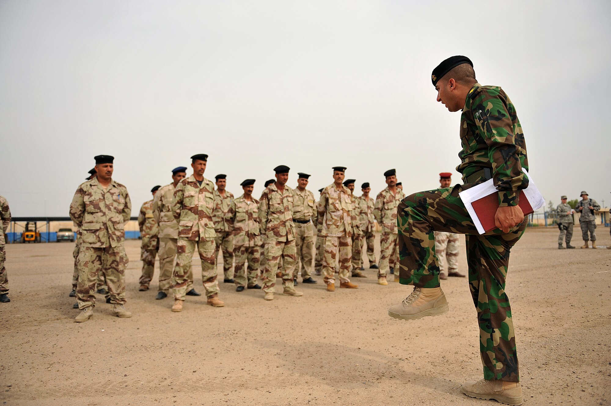 Iraqi Air Force Basic Training Instructor 1st Lt. Ammar Hamed goes over marching manuals with a group of Iraqi Air Force rehires at the Iraqi Air Force Training School in Camp Taji, Iraq, April 18, 2010. The Iraqi airmen volunteered to return to active duty through the rehire program by the Ministry of Defense.  (U.S. Air Force photo/Staff Sgt Quinton Russ/released)