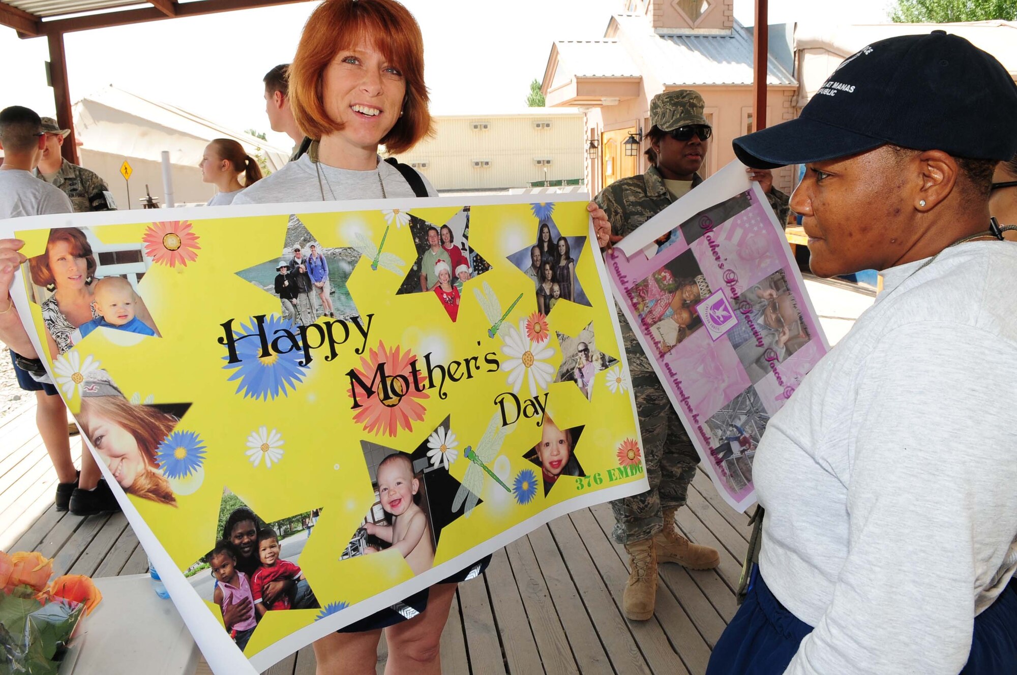 Capt. Donna Wanshon, 376th Expeditionary Medical Group clinical social worker, displays her unit?s Mother?s Day sign depicting mothers deployed in the unit and family members waiting their return back at home. The Transit Center at Manas, Kyrgyzstan, recognized Mother?s Day with a parade and barbeque, May 9, 2010. (U.S. Air Force photo by Senior Airman Nichelle Anderson/ released)