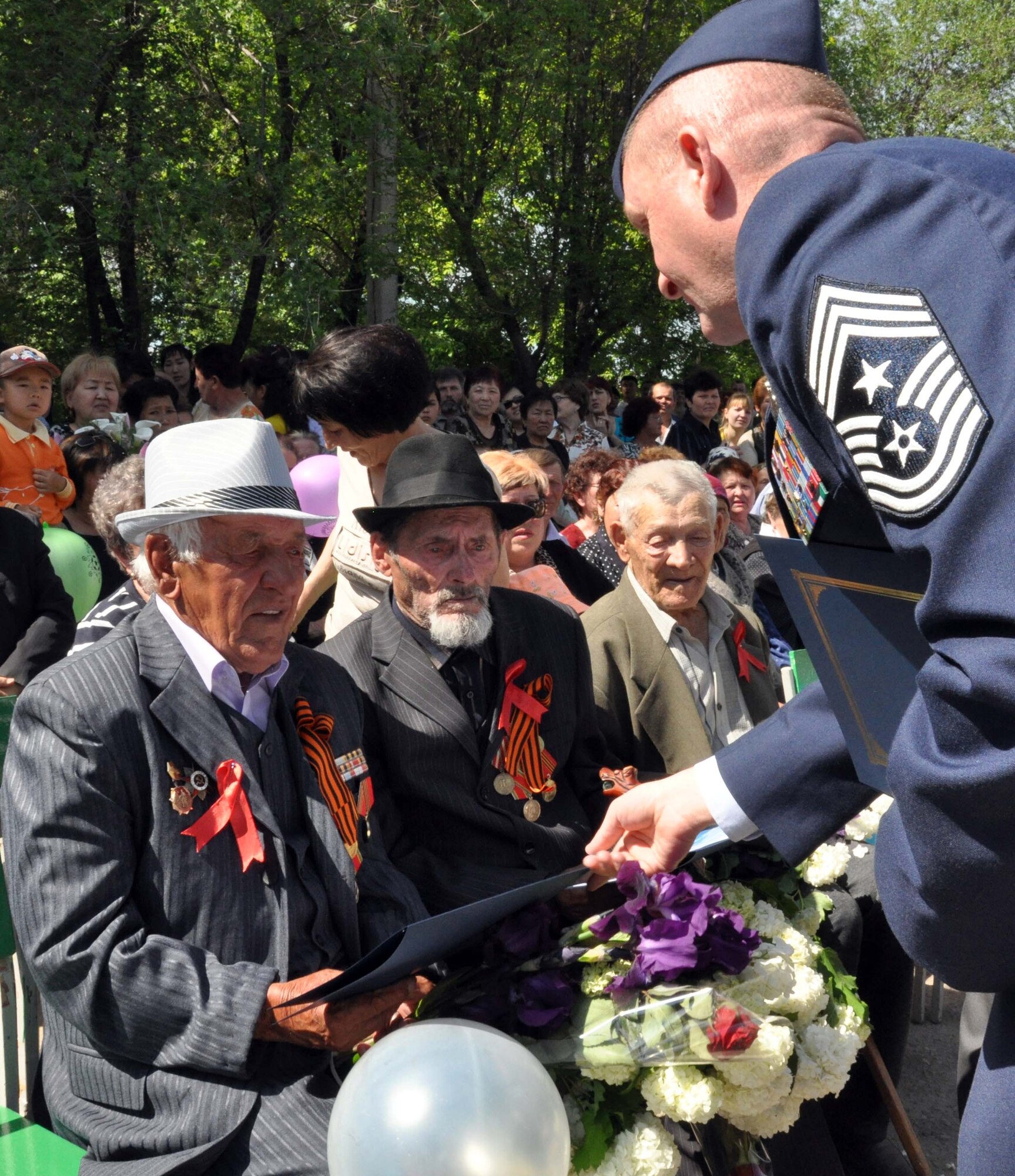 Command Chief Master Sgt. James Dowell, the enlisted leader of the Transit Center at Manas, Kyrgyzstan, presents certificates for the Kyrgyz flag which was flown over Afghanistan during a combat mission supporting Operation Enduring Freedom to decorated veterans of the Great Patriotic War (WWII) during a Victory Day celebration in Manas Village May 9, 2010. During the event, a memorial wall was unveiled with about 50 names etched in stone of village patriots who died during the war. (U.S. Air Force photo/Staff Sgt. Carolyn Viss)