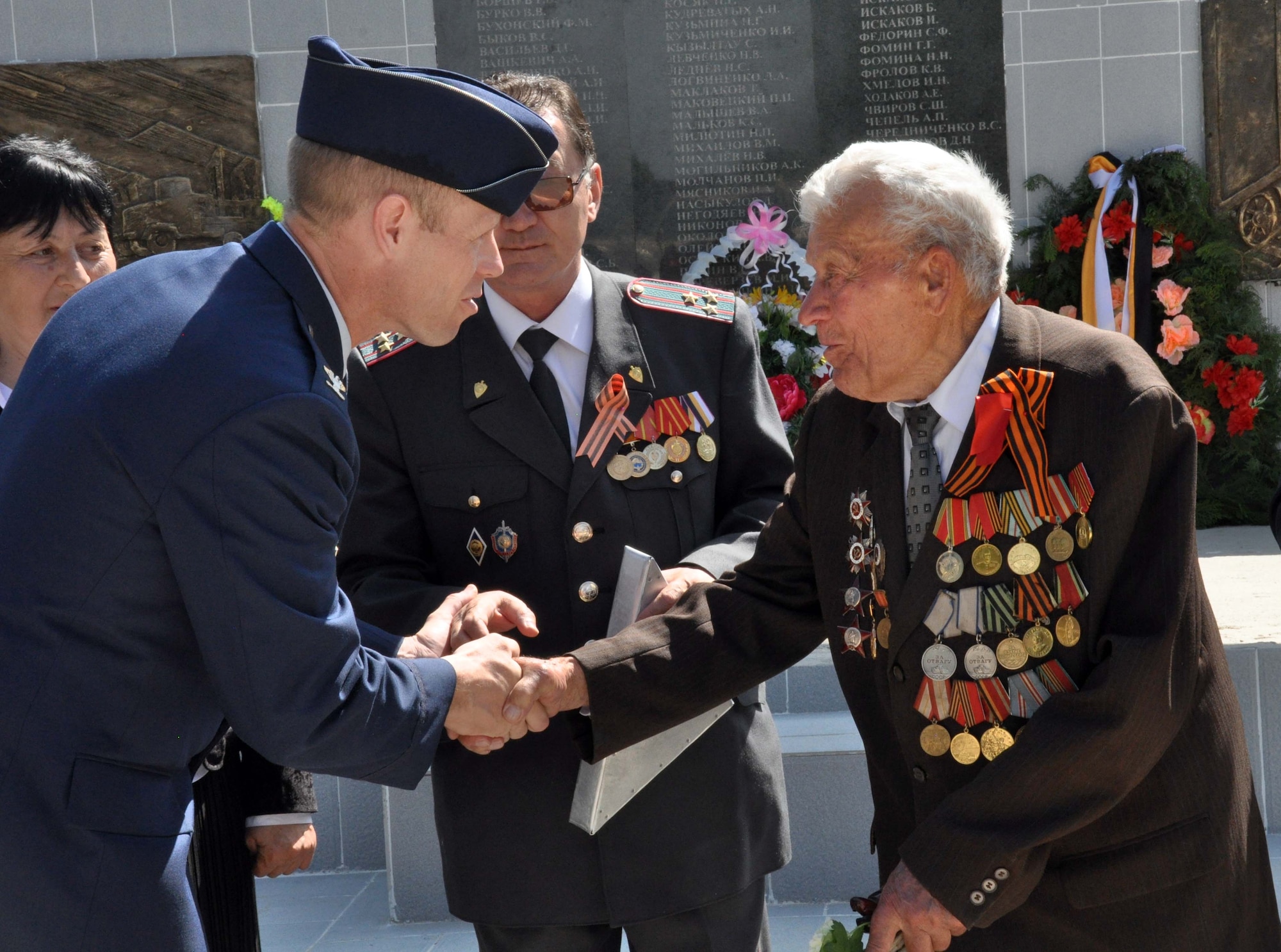 U.S. Air Force Col. Blaine Holt, the director of the Transit Center at Manas, shakes hands with a highly-decorated veteran of the Great Patriotic War (WWII) after presenting a Kyrgyz flag to Mr. Beshimbaev Kabylbek, the Mayor of Manas Village, Kyrgyzstan (center), during a Victory Day ceremony celebrating the end of the Nazi regime in 1945. The flag was flown over Afghanistan during a combat mission supporting Operation Enduring Freedom, and Colonel Holt also presented certificates for the flag to four living WWII veterans from Manas who were honored during the ceremony. (U.S. Air Force photo/Staff Sgt. Carolyn Viss)