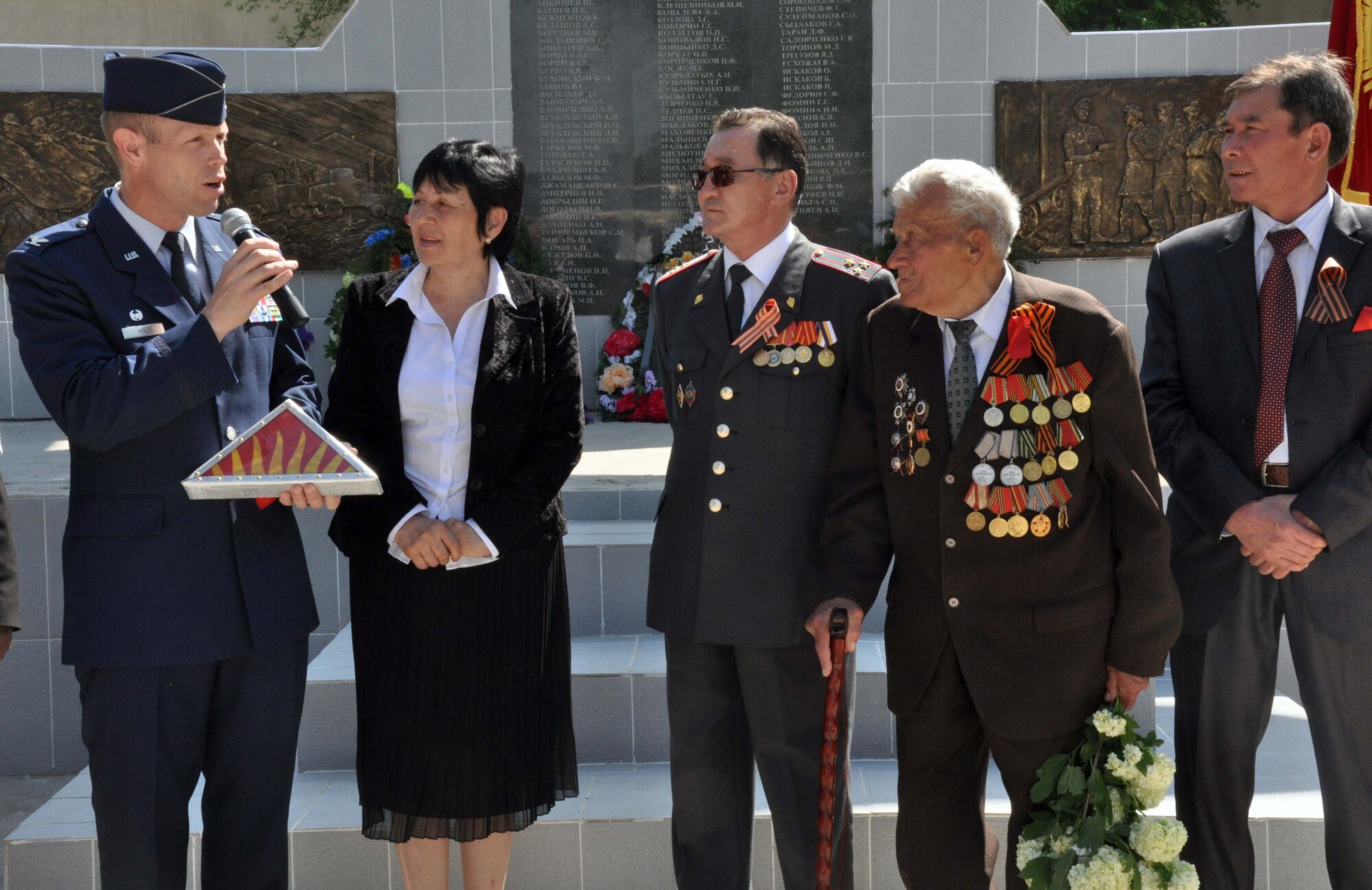 U.S. Air Force Col. Blaine Holt, the director of the Transit Center at Manas, presents a Kyrgyz flag which was flown over Afghanistan during a combat mission supporting Operation Enduring Freedom to Mr. Beshimbaev Kabylbek, the Mayor of Manas Village, Kyrgyzstan (center), during a Victory Day ceremony celebrating the end of the Great Patriotic War (WWII) and the Nazi regime in 1945. Colonel Holt also presented certificates for the flag to four living WWII veterans from Manas, who were honored during the ceremony. (U.S. Air Force photo/Staff Sgt. Carolyn Viss)