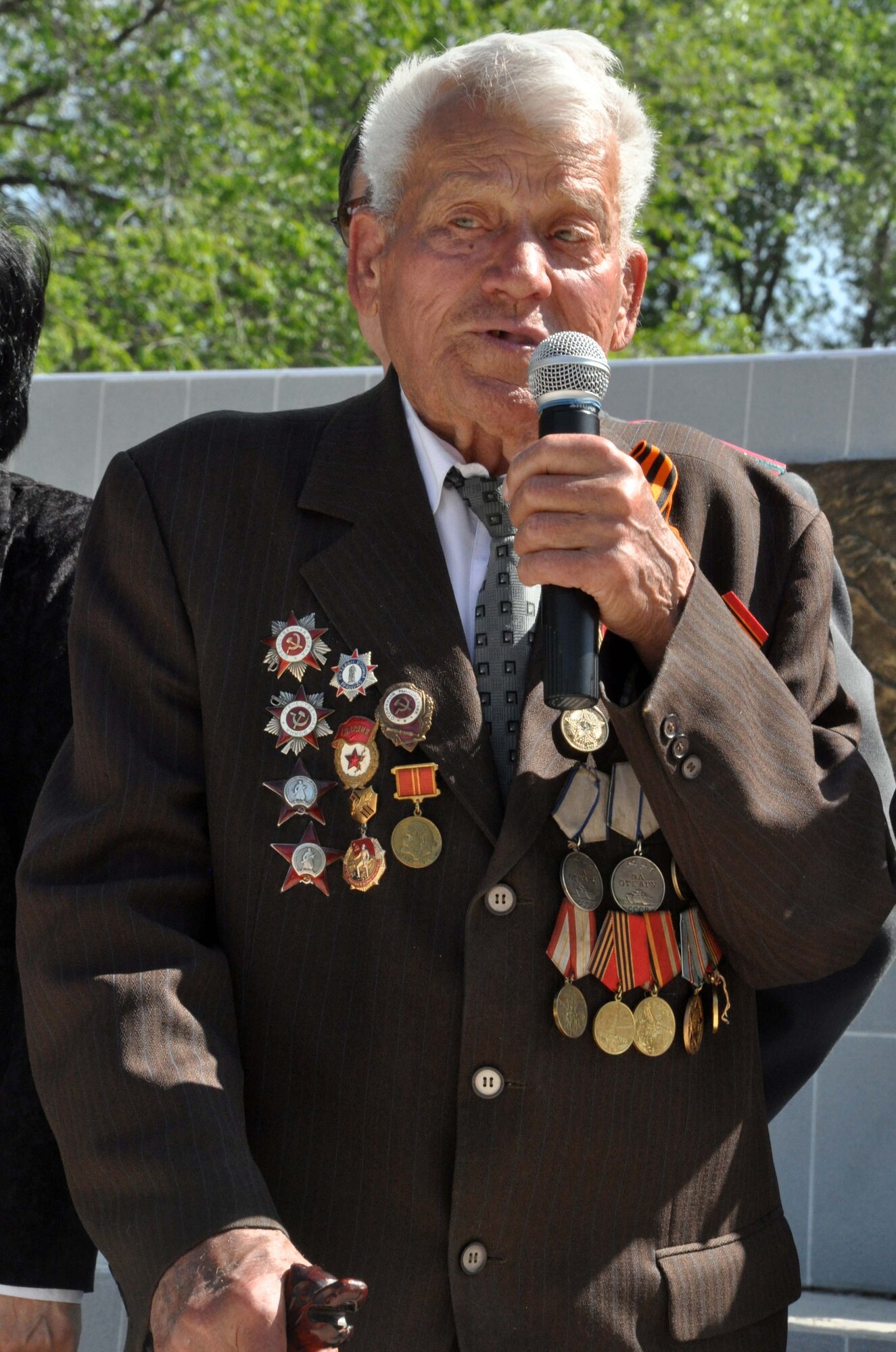 A highly-decorated veteran of the Great Patriotic War (WWII) speaks to the people of Manas Village, Kyrgyzstan, during a Victory Day ceremony May 9, 2010. U.S. Air Force Col. Blaine Holt, the director of the Transit Center (center), also attended the event, which was hosted by the Mayor of Manas, Mr. Beshimbaev Kabylbek. During the ceremony, celebrating of the end of the Nazi regime, a memorial wall was unveiled with about 50 names etched in stone of village patriots who died during the war. (U.S. Air Force photo/Staff Sgt. Carolyn Viss)