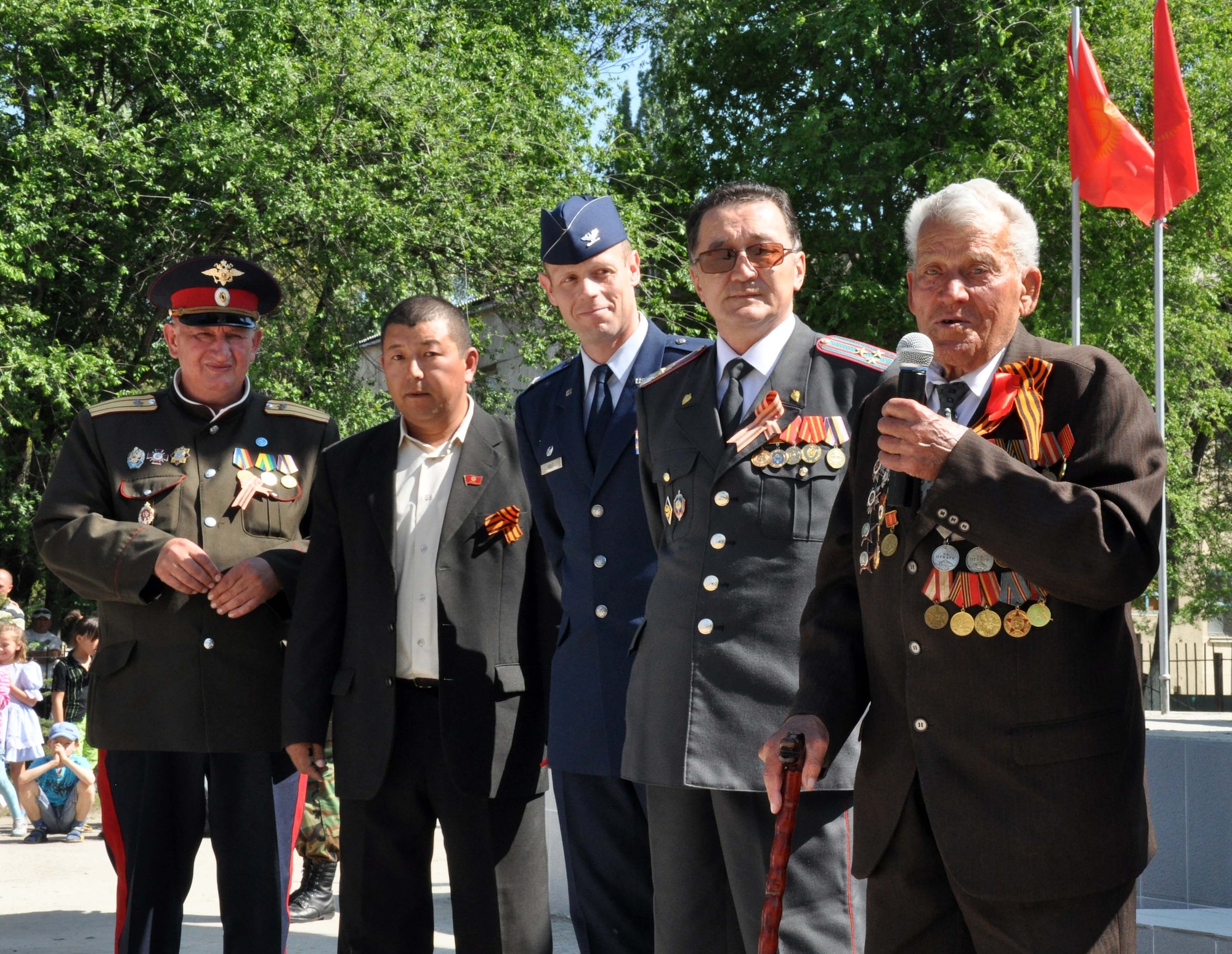 A highly-decorated veteran of the Great Patriotic War (WWII) speaks to the people of Manas Village, Kyrgyzstan, during a Victory Day ceremony May 9, 2010. U.S. Air Force Col. Blaine Holt, the director of the Transit Center (center), also attended the event, which was hosted by the Mayor of Manas, Mr. Beshimbaev Kabylbek. During the ceremony, celebrating of the end of the Nazi regime, a memorial wall was unveiled with about 50 names etched in stone of village patriots who died during the war. (U.S. Air Force photo/Staff Sgt. Carolyn Viss)