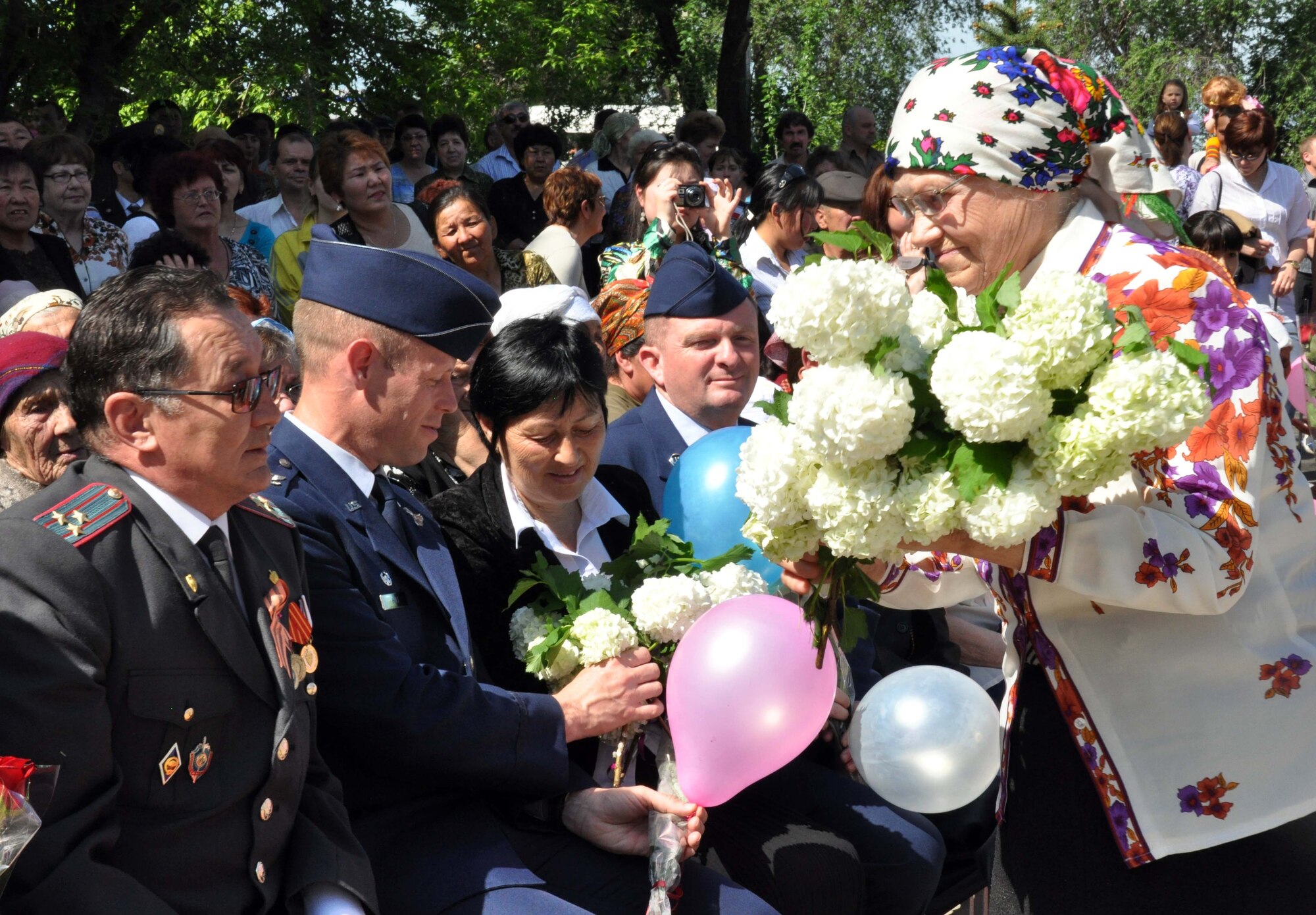 A Kyrgyz woman presents flowers and balloons to the Mayor of Manas, Mr. Beshimbaev Kabylbek; Col. Blaine Holt, the director of the Transit Center at Manas; and Chief Master Sgt. James Dowell, the Transit Center?s command chief, during a Victory Day ceremony May 9, 2010. The ceremony, which celebrated of the end of the Nazi regime, was also attended by four highly-decorated WWII veterans from Manas, Kyrgyzstan. (U.S. Air Force photo/Staff Sgt. Carolyn Viss)