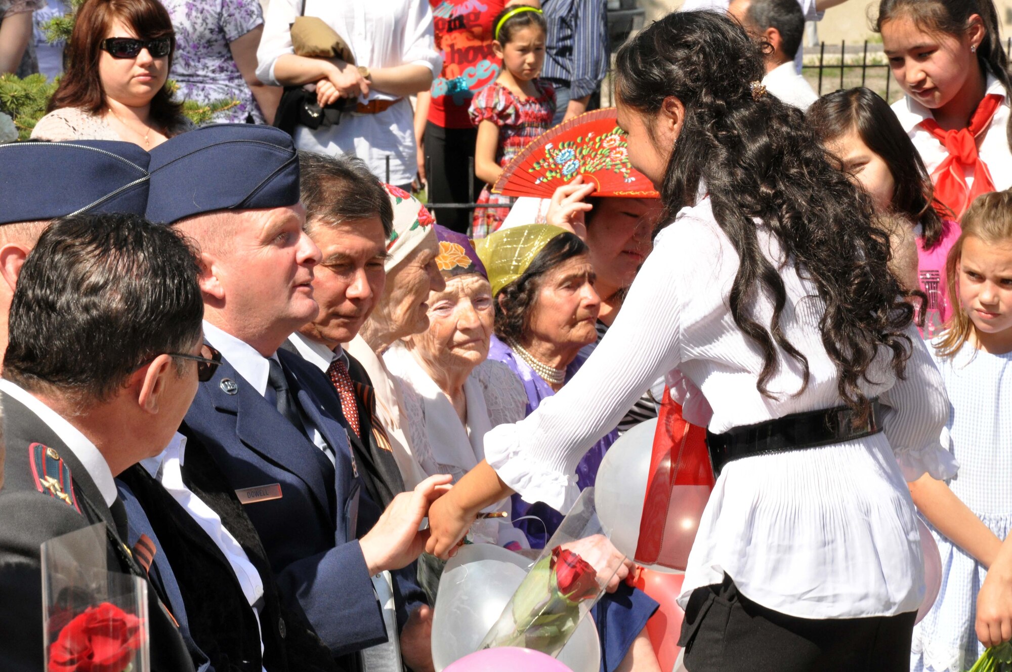 A Kyrgyz girl presents flowers and balloons to Command Chief Master Sgt. James Dowell, the enlisted leader of the Transit Center at Manas, Kyrgyzstan, during a Victory Day ceremony in Manas Village May 9, 2010. This day marks the end of WWII and the Nazi regime in 1945. During the event, four living veterans from Manas were honored, and a memorial wall was unveiled with about 50 names etched in stone of village patriots who died during the war. (U.S. Air Force photo/Staff Sgt. Carolyn Viss)