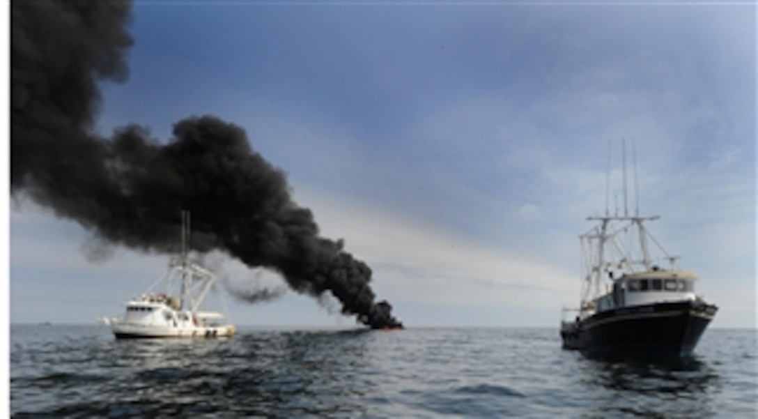 Shrimp boats Gulf Rambler (left) and Mark and Jace pull a hydro oil boom during a controlled fire in the Gulf of Mexico on May 7, 2010.  The U.S. Coast Guard is working with BP, Gulf residents and other federal agencies to slow the spread of oil following the explosion of the Deepwater Horizon oil rig on April 20, 2010.  