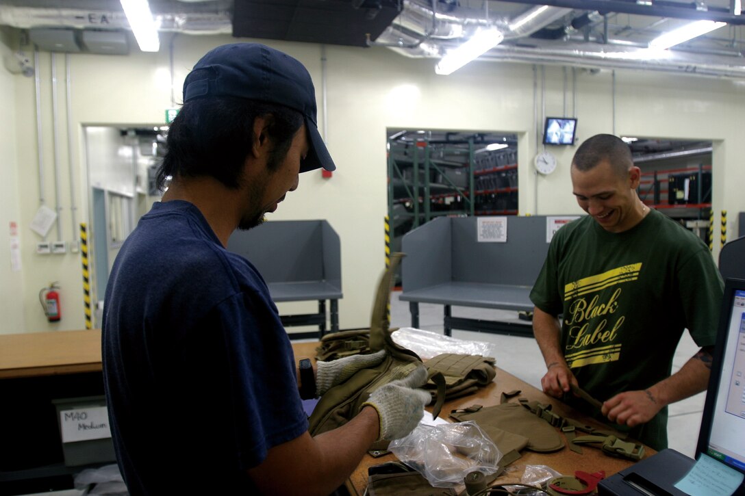 Shiro Gima, left, warehouse specialist, Lion Vallen Industries, Camp Schwab Individual Issue Facility, Consolidated Storage Program, processes gear being returned by Petty Officer 3rd Class Jesse Coddington, hospital corpsman, Combat Assault Battalion, 3rd Marine Division, III Marine Expeditionary Force, in the new IFF on Camp Schwab which hosted an open house Tuesday.