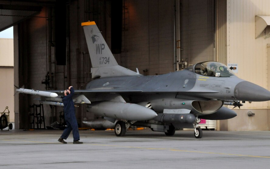 Senior Airman Ken Filewich, a crewchief with the 80th Aircraft Maintenance Unit, "throws snakes" as Capt. Jesse Proctor, 80th Fighter Squadron F-16 Fighting Falcon pilot, taxis out of a hangar during Red Flag-Alaska April 16. "Throwing snakes" is a visual way for 80th FS Headhunters, known as the "Juvats," to show their motto, "Crush 'Em." Airman Filewich and Captain Proctor are deployed from the 8th Fighter Wing, Kunsan Air Base, Republic of Korea. Red Flag-Alaska is a field training exercise that provides joint offensive counter-air, interdiction, close air support, and large force employment training in a simulated combat environment. (U.S. Air Force photo/Capt. Shannon Collins)