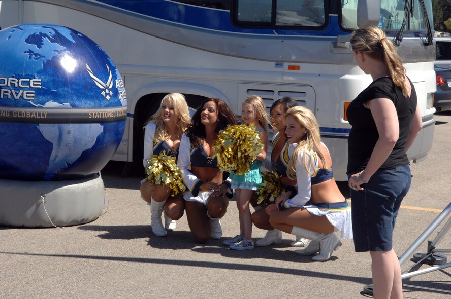 A young girl poses with the San Diego Chargers cheerleaders at the March Field AirFest, March Air Reserve Base, Calif., May 1, 2010. The AirFest is a bi-annual, two-day event featuring military and civilian aerial performances and static displays of modern and historic aircraft. (U.S. Air Force photo by Staff Sgt. Angel Gallardo/Released)
