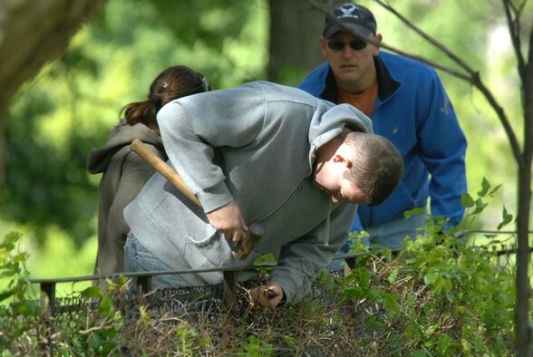 OFFUTT AIR FORCE BASE, Neb. -- Senior Airman Ross Ray, 55th Operations Support Squadron, repairs fence linkage while Senior Master Sgt. Steven Schwerdtfeger, 625th Strategic Operations Squadron, looks on at the Henry Doorly Zoo in Omaha, Neb., May 8 during the zoo's annual clean up day. Both Airmen were part of a large group from Offutt who volunteered to help clean the zoo. U.S. Air Force photo by Delanie Stafford