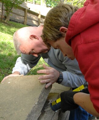 OFFUTT AIR FORCE BASE, Neb.-- Don Smith (left), 55th Communications Squadron, and Ryan Newman (right), the son of Maj. Dale Newman, 710th Medical Squadron, repair loose retaining wall cap stones during the Annual Zoo Clean Up Day at the Henry Doorly Zoo May 8 in Omaha, Neb. The Airmen were part of a large group from Offutt who volunteered to help clean the zoo. U.S. Air Force photo by Delanie Stafford