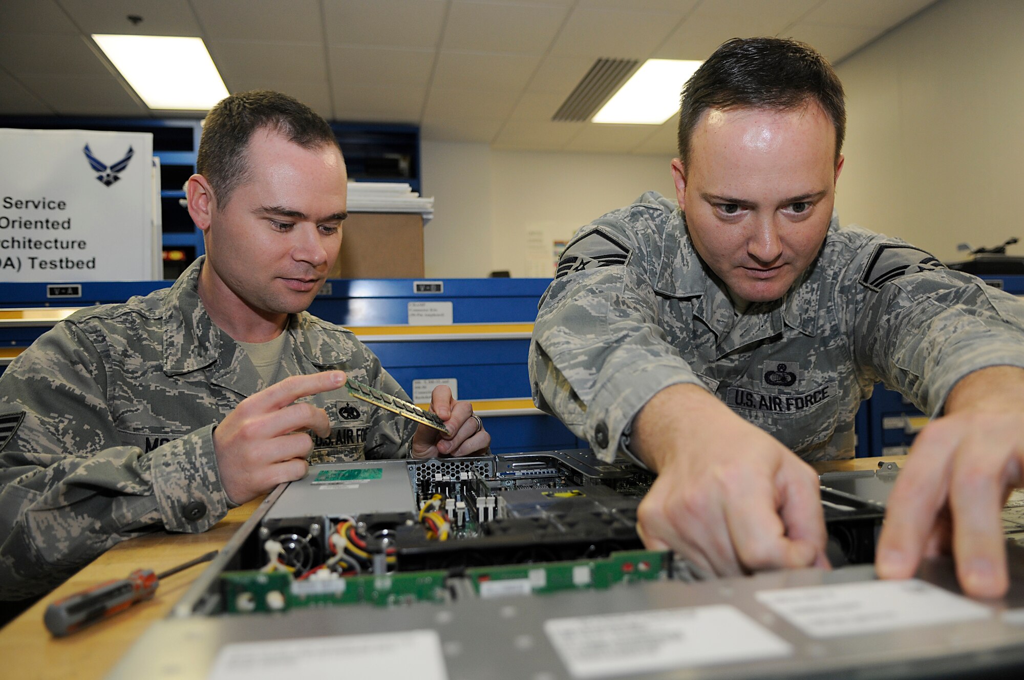 Master Sgt. Erik Weaver (right) and Staff Sgt. Nathan Moore inspect computer equipment to validate the system’s capabilities.  (U.S. Air Force Photo by Senior Airman Brian J. Ellis)