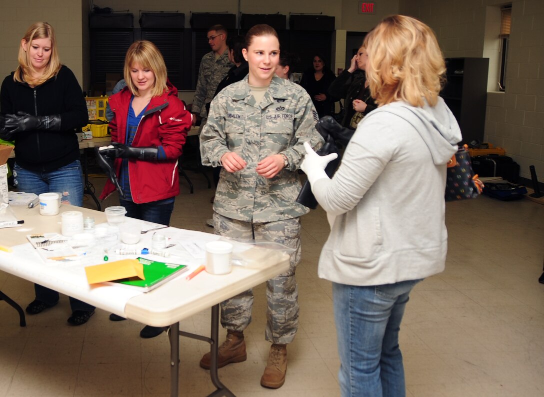 ELLSWORTH AIR FORCE BASE, S.D. -- (Left to right) Bailey Vickery, wife of Staff Sgt. Joshua Vickery, 28th Civil Engineer Squadron explosive ordnance disposal technician, Erin Terlop, wife of Airman 1st Class Paul Terlop, 28 CES heavy equipment operator, Staff Sgt. Jessica Aadalen, 28 CES emergency management technician and Neva Grabow, wife of Senior Airman Beau Grabow, 28 CES EOD technician, put on chemical protective gloves during a demonstration for spouse day, May 7.  Spouse day gave husbands and wives of Ellsworth Airmen the opportunity to see what their spouse does for the Air Force. (U.S. Air Force/photo Air man 1st Class Anthony Sanchelli)
