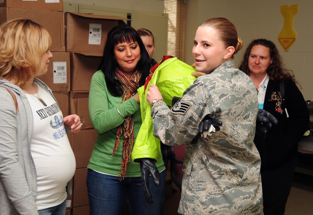 ELLSWORTH AIR FORCE BASE, S.D. -- Staff Sgt. Jessica Aadalen, 28th Civil Engineer Squadron emergency management technician, helps Sheryl Cronan, wife of Chief Master Sgt. Robert Cronan, 28 CES chief enlisted manager, with chemical protection gloves during a demonstration for spouse day, May 7.  Spouses of Ellsworth Airmen were given the chance to see firsthand what their husband or wife does for the Air Force. (U.S. Air Force/photo Air man 1st Class Anthony Sanchelli)
