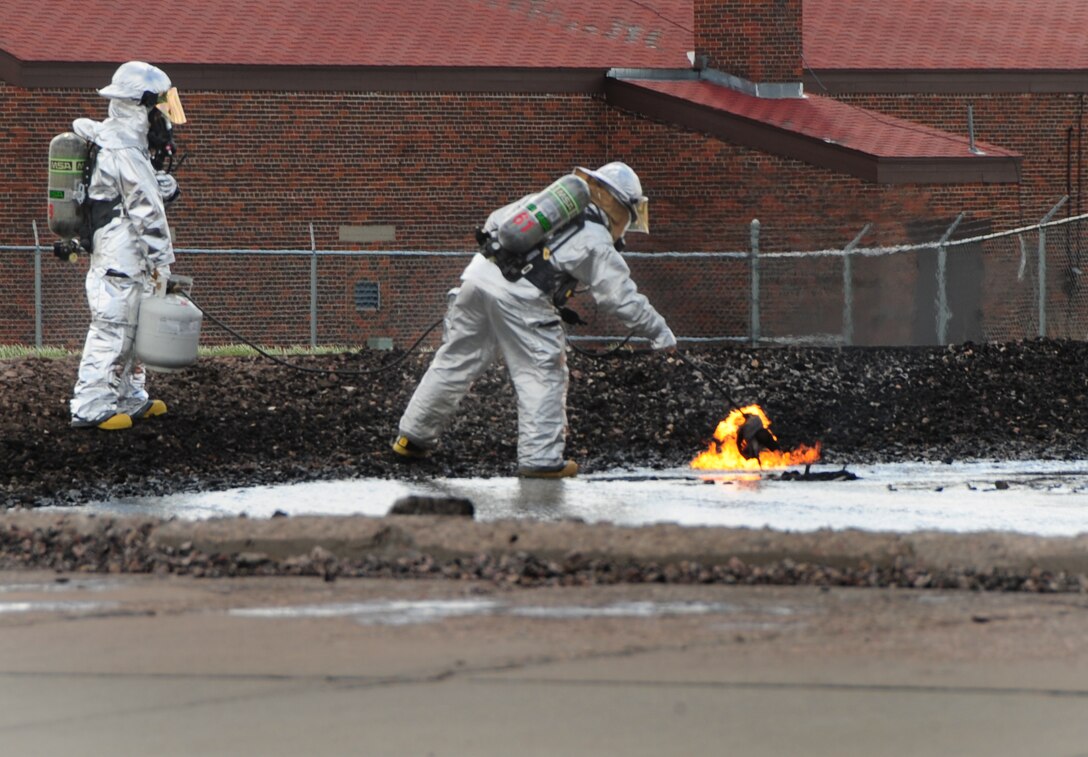 ELLSWORTH AIR FORCE BASE, S.D. -- (Left to right) Airman 1st Class Samantha Tremblay and Senior Airman Daniel Zimbardo, 28th Civil Engineer Squadron firefighters, ignite fuel in a burn pit during a demonstration for spouse day, May 7.  Spouse day was a base-wide event where all spouses of Ellsworth Airmen were encouraged to explore their spouse’s career field. (U.S. Air Force/photo Air man 1st Class Anthony Sanchelli)

