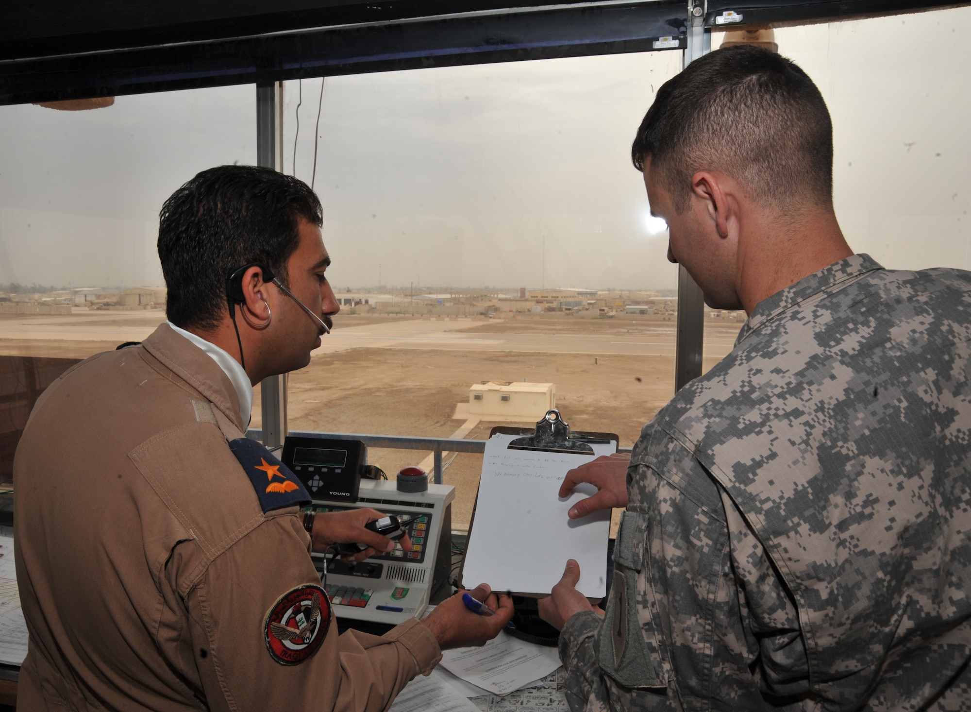 U.S. Army Spc. Cyrus Haines, right, passes air traffic and weather advisory notes to Iraqi Air Force 2nd Lt. Shorsh Abdillah at Camp Taji, Iraq April 17, 2010.  ITAM is in the process of transferring all operations to the Iraqi military for the U.S. draw down.  Spc. Haines is assigned to 1st Infantry, 2nd Battalion, 1st Division Fox Company, Combat Aviation Brigade.  (U.S. Air Force photo/Staff Sgt Quinton Russ/released)