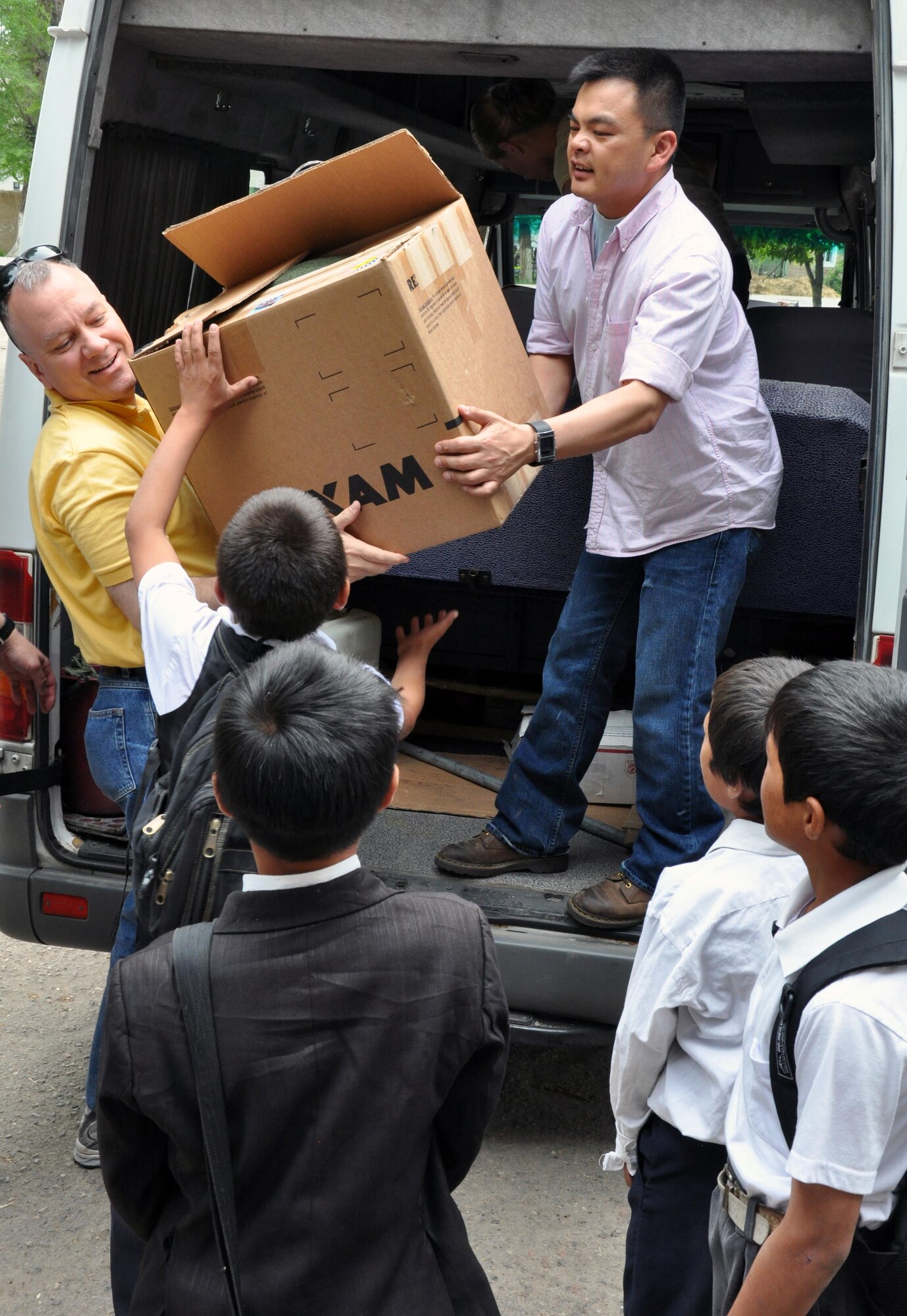 Capt. Tom Mulka and Ch. (Maj.) Michael Morris unload a van full of clothing with the help of Kyrgyz students from the Jany-Pakhta School during a humanitarian assistance visit May 11, 2010. Jany-Pakhta Schools are sponsored by the Manas Area Benefit Outreach Society, and Airmen visit regularly to play with children and give them textbooks and other items the schools need. (U.S. Air Force photo/Staff Sgt. Carolyn Viss)