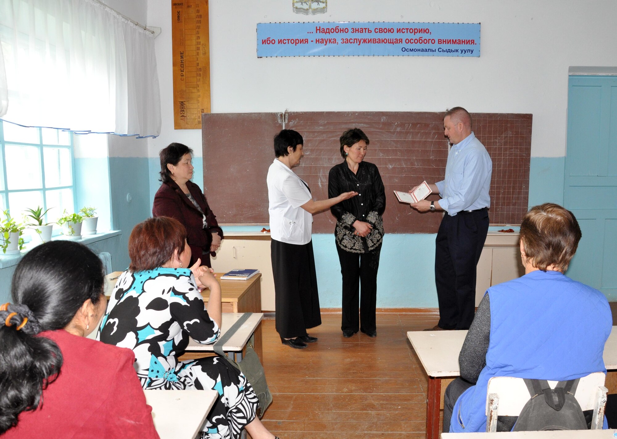 The Jany-Pakhta School director requested that Command Chief Master Sgt. Jim Dowell, the enlisted leader of the Transit Center at Manas, Kyrgyzstan, present one of the teachers with a certificate of appreciation during a humanitarian assistance visit May 11, 2010. Jany-Pakhta Schools are sponsored by Manas Area Benefit Outreach Society, and Airmen from the Transit Center visit regularly to play with children and give them textbooks and other items the schools need. (U.S. Air Force photo/Staff Sgt. Carolyn Viss)