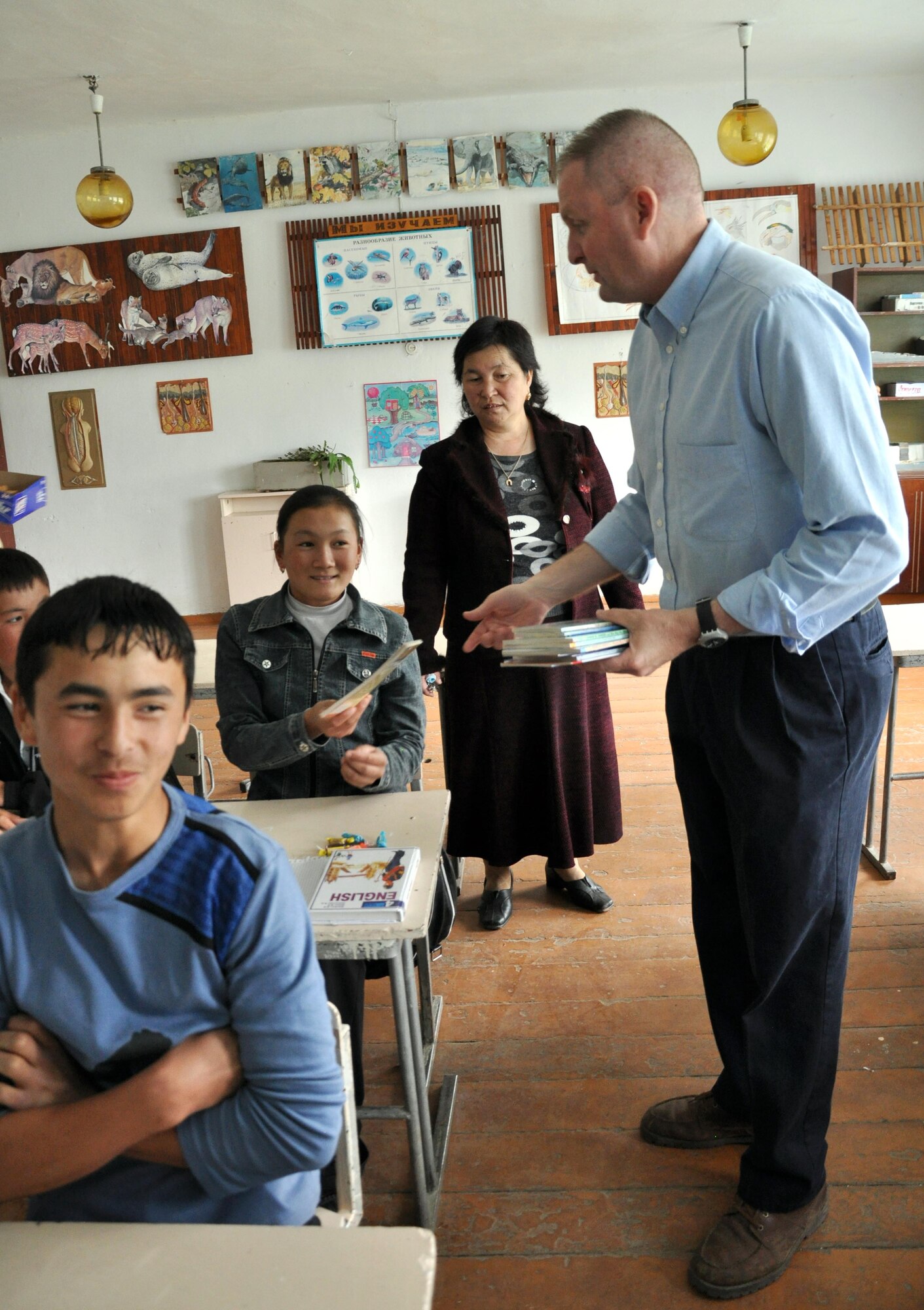 Command Chief Master Sgt. James Dowell, the enlisted leader of the Transit Center at Manas, Kyrgyzstan, gives a book to a young girl at the Jany-Pakhta School, Kyrgyzstan, during a humanitarian assistance visit May 11, 2010. Jany-Pakhta Schools are sponsored by Manas Area Benefit Outreach Society, and Airmen from the Transit Center at Manas visit regularly to play with children and give them textbooks and other items the schools need. (U.S. Air Force photo/Staff Sgt. Carolyn Viss)