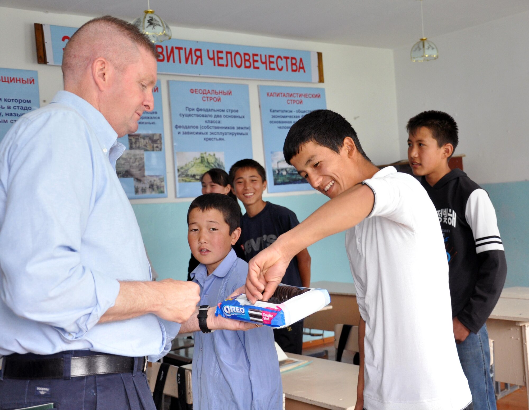 Command Chief Master Sgt. James Dowell, the enlisted leader of the Transit Center at Manas, Kyrgyzstan, gives cookies to a young man at the Jany-Pakhta School, Kyrgyzstan, during a humanitarian assistance visit May 11, 2010. Jany-Pakhta Schools are sponsored by Manas Area Benefit Outreach Society, and Airmen from the Transit Center at Manas visit regularly to play with children and give them textbooks and other items the schools need. (U.S. Air Force photo/Staff Sgt. Carolyn Viss)