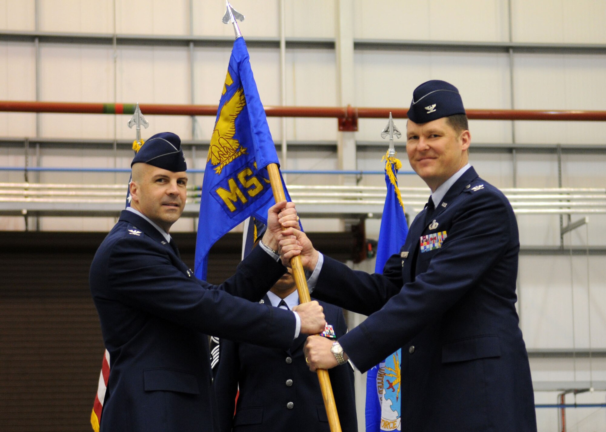 RAF MILDENHALL, England – Col. Chad Manske, 100th Air Refueling Wing commander (left), delivers the 100th Mission Support Group guidon to Col. David Doe to signify his assumption of command of the group during a change of command ceremony in Hangar 814 May 7. (U.S. Air Force photo/ Staff Sgt. Jerry Fleshman)