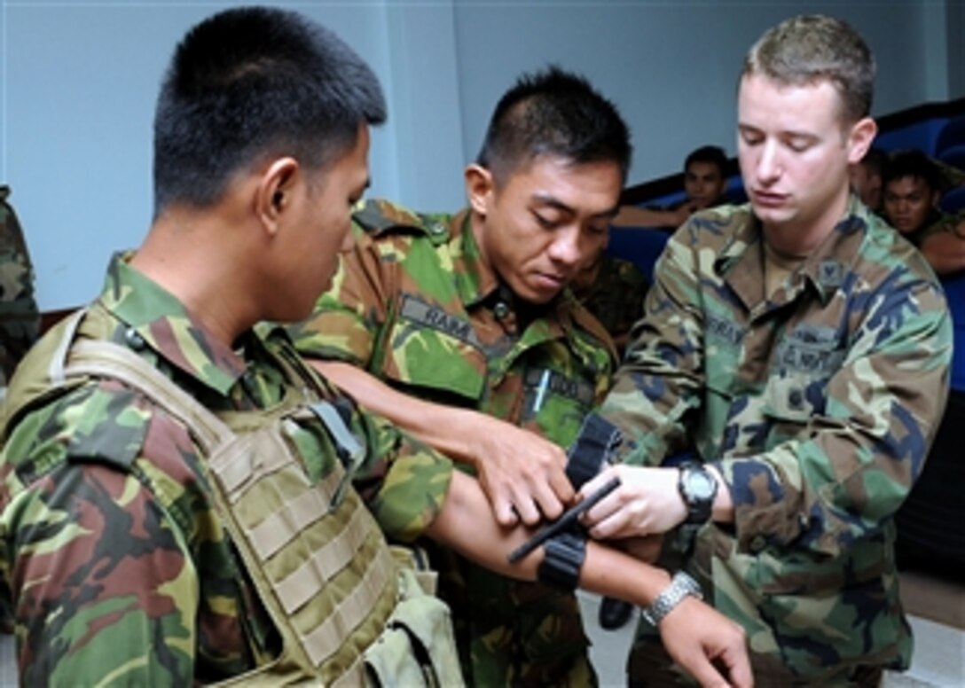 U.S. Navy Petty Officer 2nd Class Caleb Murray (right), of Riverine Squadron 1, works with two members of the Royal Brunei Navy Support Squadron to demonstrate the proper use of the tourniquet he carries in his first aid kit when he’s on a mission in Muara, Brunei, on May 5, 2010.  The U.S. and Brunei sailors are learning about the other service's equipment and how they carry out their similar missions during Cooperation Afloat Readiness And Training Brunei 2010.  Cooperation Afloat Readiness is an annual bilateral exercise entering its 16th year in Southeast Asia.  