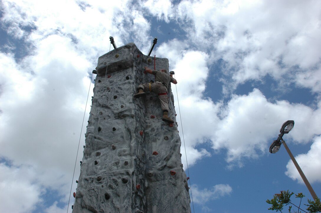 Staff Sgt. Robert Moran, Postal Chief, Headquarters and Service Battalion, tackles the rock wall at the Fitness and Wellness Expo, Tuesday, May 11.