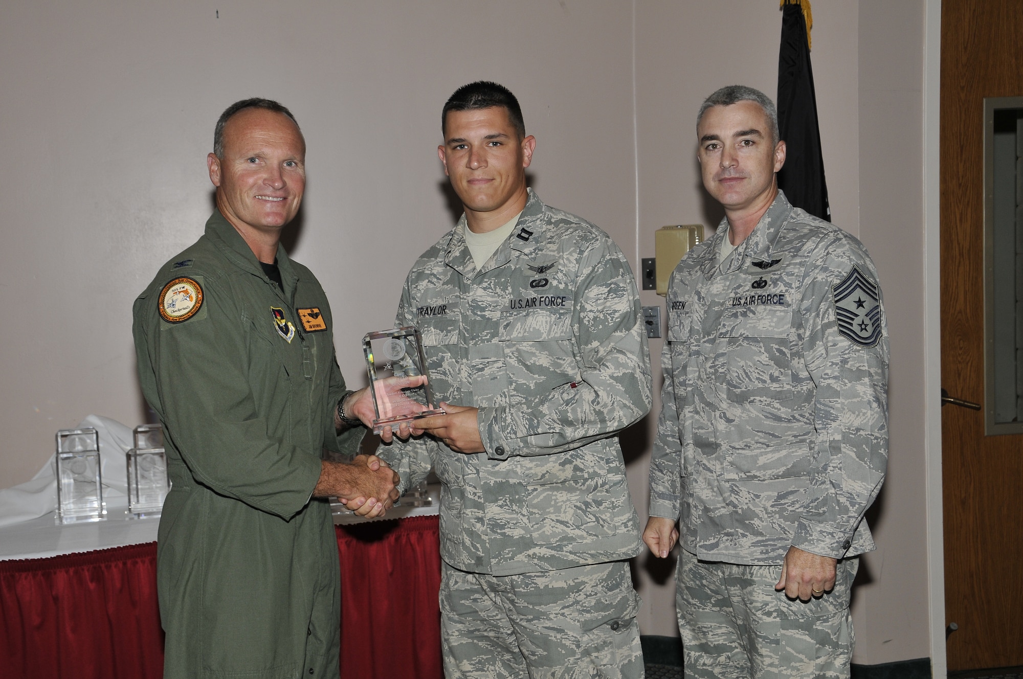 Colonel James Browne, 325th Fighter Wing commander, presents Captain Alfred Traylor, Det 1, 823rd RED HORSE project manager air base sciences, the Associate Unit Company Grade Officer of the Quarter award, as Chief Master Sgt. Jackie Greene, 325th FW command chief, looks on.
