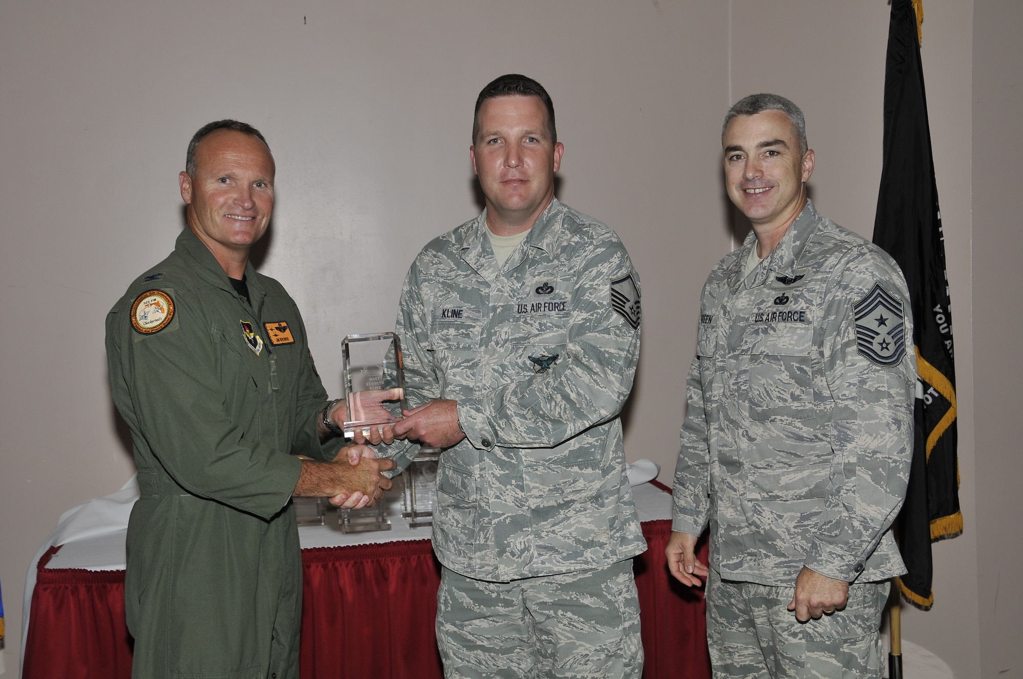 Colonel James Browne, 325th Fighter Wing commander, presents Master Sergeant Kenneth Kline, Det 1, 823rd RED HORSE section chief emergency services contingency training, the Associate Unit Senior NCO of the Quarter award, as Chief Master Sgt. Jackie Greene, 325th FW command chief, looks on.
