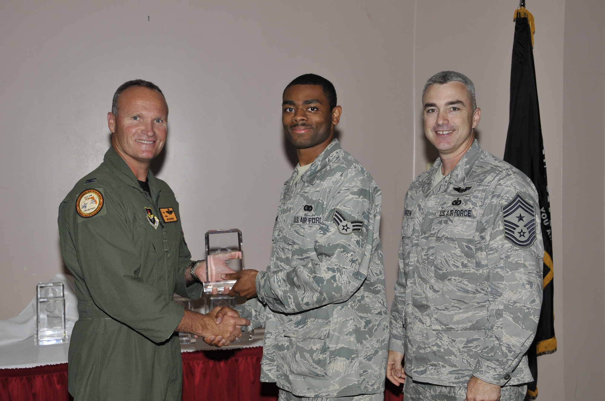 Colonel James Browne, 325th Fighter Wing commander, presents Senior Airman Ryan McCall, 53rd Test Support Squadron client systems technician, the Associate Unit Airman of the Quarter award, as Chief Master Sgt. Jackie Greene, 325th FW command chief, looks on.