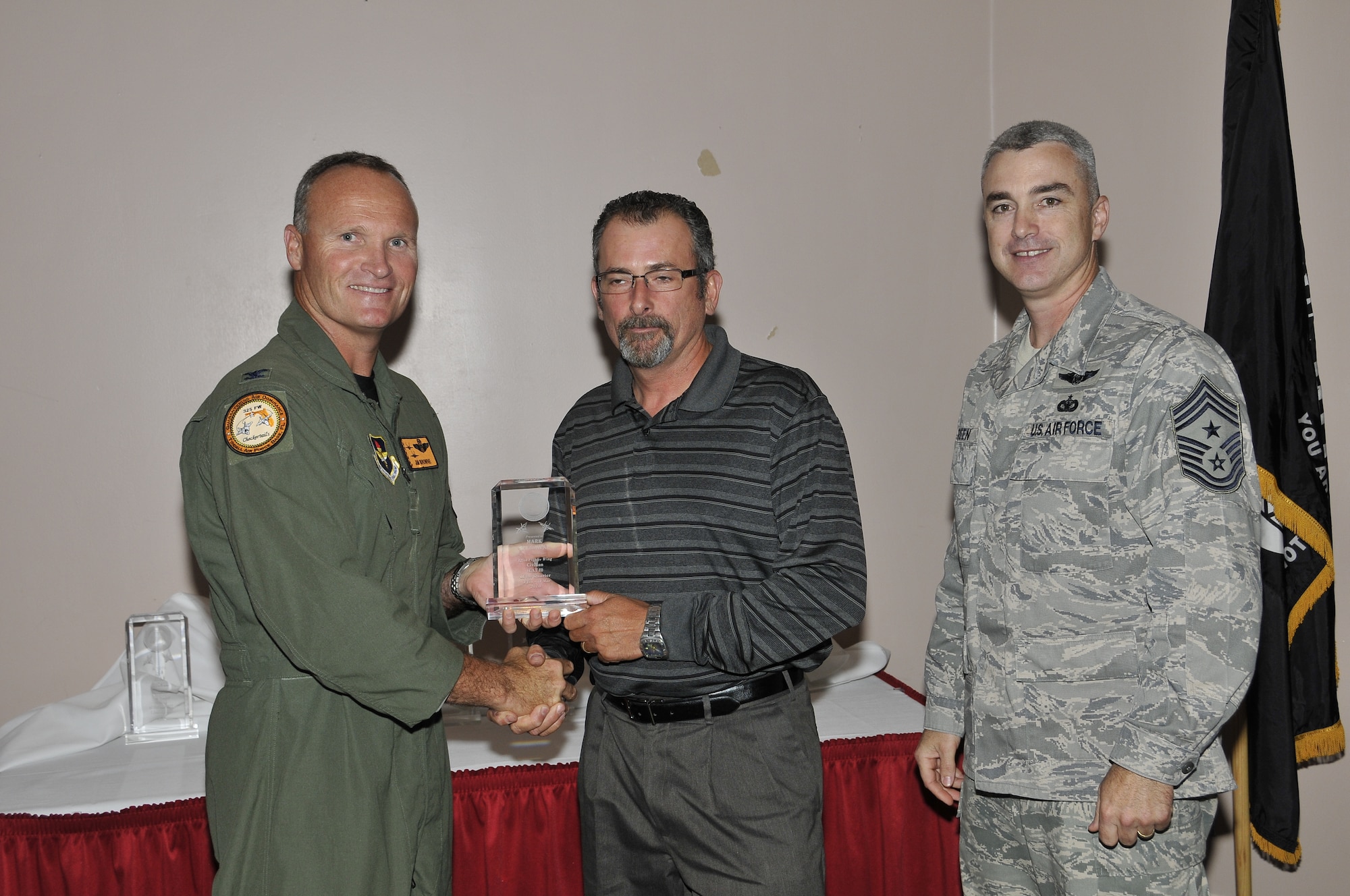 Colonel James Browne, 325th Fighter Wing commander, presents Mr. Mark Schenavar, 325th Operations Group special security representative, the 325th FW Civilian Category II of the Quarter award, as Chief Master Sgt. Jackie Greene, 325th FW command chief, looks on.