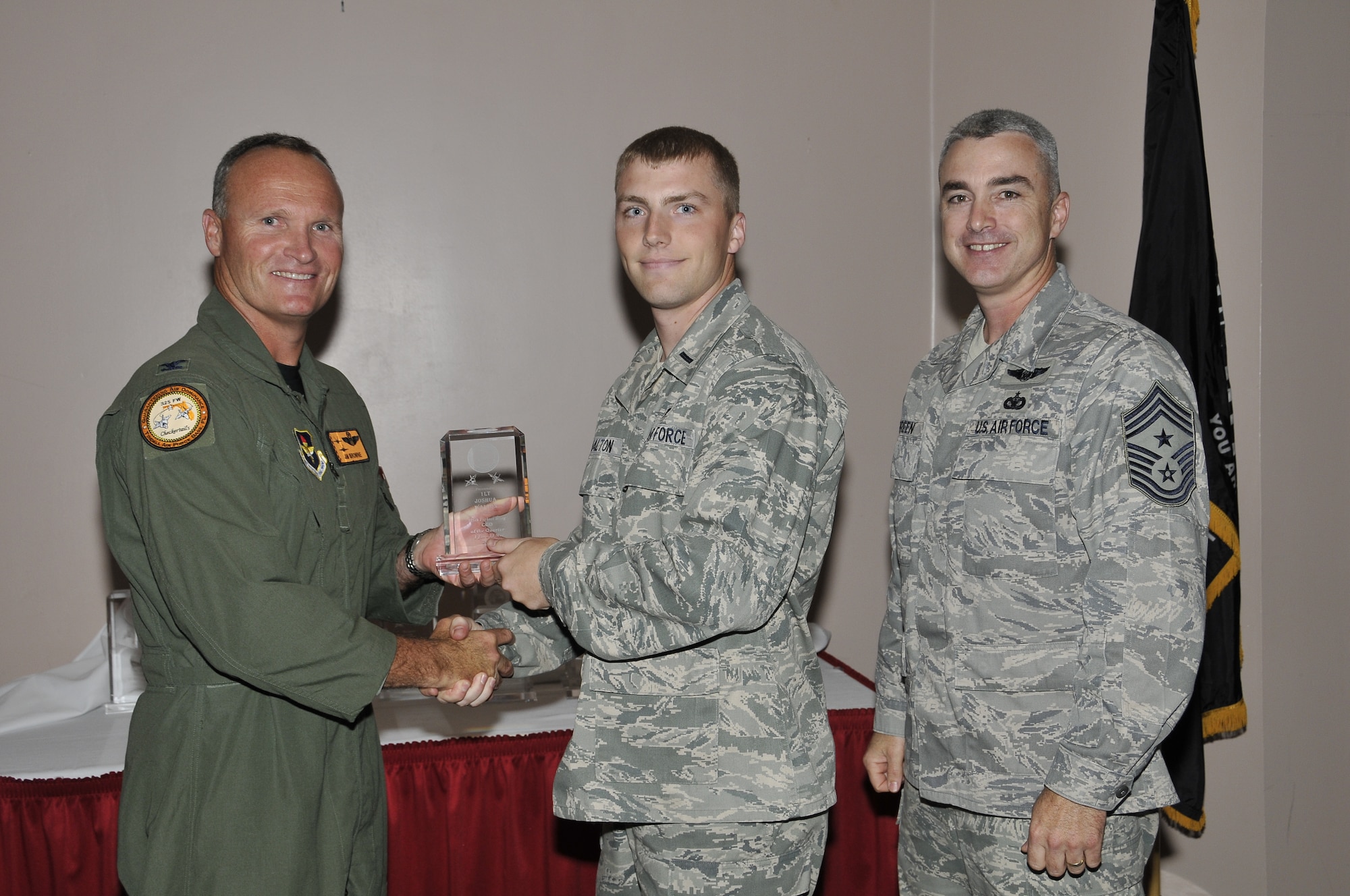 Colonel James Browne, 325th Fighter Wing commander, presents 1st Lt. Joshua Walton, 95th Aircraft Maintenance Unit assistant officer in charge, the 325th FW Company Grade Officer of the Quarter award, as Chief Master Sgt. Jackie Greene, 325th FW command chief, looks on.