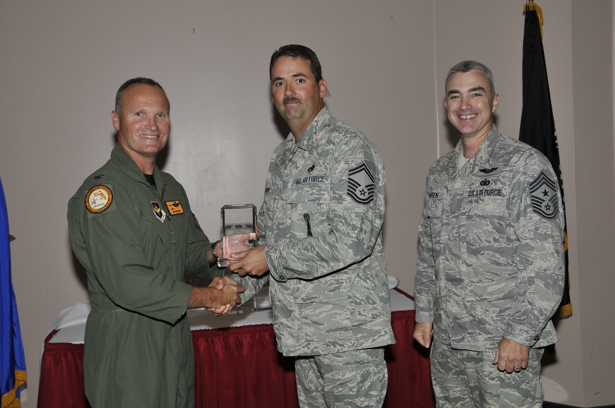 Colonel James Browne, 325th Fighter Wing commander, presents Senior Master Sgt. Bradly Coon, 325th Maintenance Group weapons superintendent, the 325th FW Senior NCO of the Quarter award, as Chief Master Sgt. Jackie Greene, 325th FW command chief, looks on.