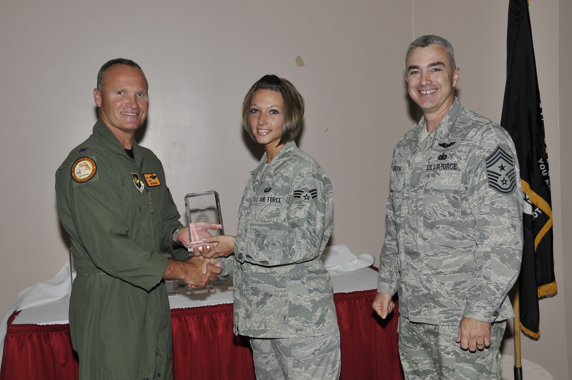 Colonel James Browne, 325th Fighter Wing commander, awards Senior Airman Christen Abner, 325th Comptroller Squadron finance customer service technician, the 325th FW Airman of the Quarter, as Chief Master Sgt. Jackie Greene, 325th FW command chief, looks on.