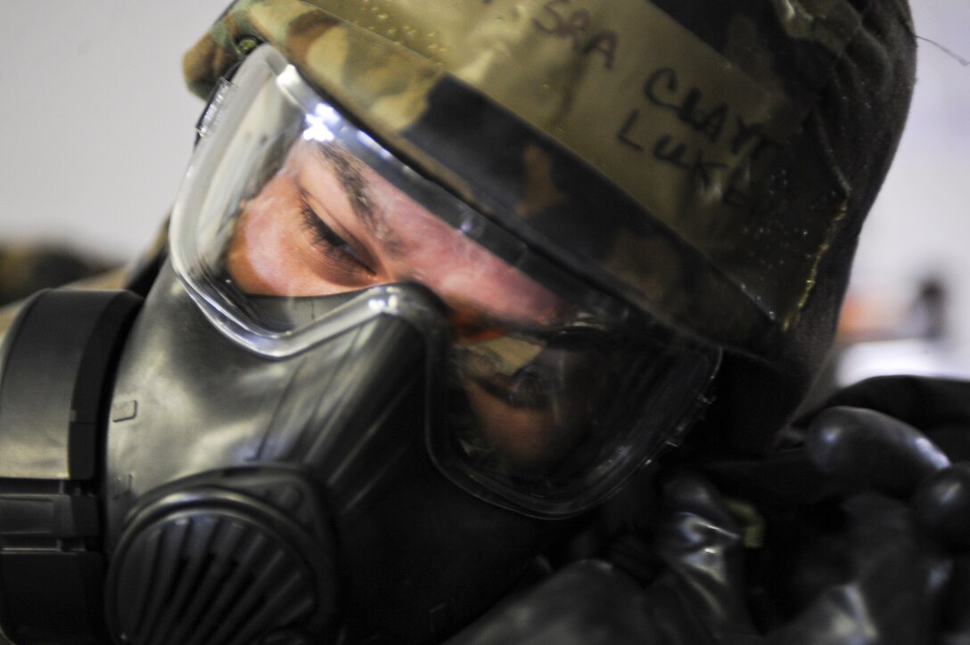 ELLSWORTH AIR FORCE BASE, S.D. — Senior Airman Clayton Luker, 28th Medical Group medical technician, fastens his helmet while donning Mission Oriented Protective Posture gear during the the Phase II Operational Readiness Exercise, May 12. MOPP 4 consists of chemical and biological warfare jackets and pants, protective rubber boots, rubber gloves and gas mask. (U.S. Air Force photo/Senior Airman Adam Grant)
