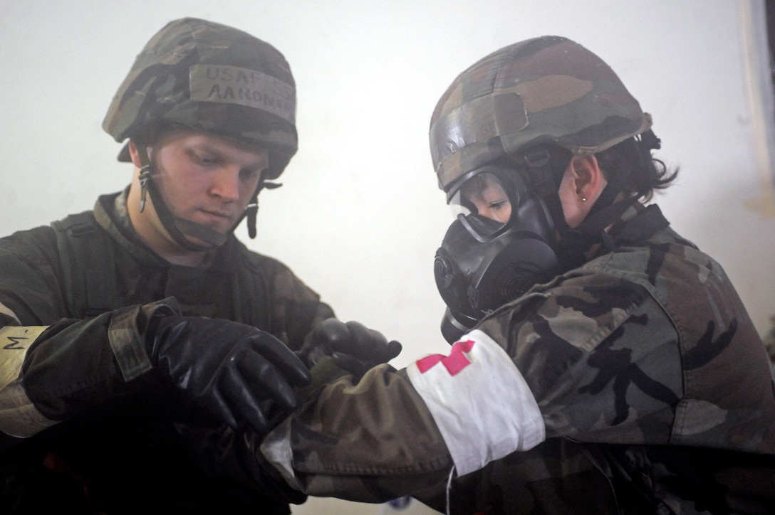 ELLSWORTH AIR FORCE BASE, S.D. – (Left) Staff Sgt. Aaron Smith, 28th Medical Operations Squadron ambulance services technician, assists Staff Sgt. Mellisa McQuagge, 28 MDOS ambulance services technician, with putting on her mission oriented protective posture gear during a Phase II Operational Readiness Exercise, May 12. A Phase II ORE is designed to prepare Airmen for deployed operations, including potential chemical attacks. (U.S. Air Force photo/Airman 1st Class Matthew Flynn)