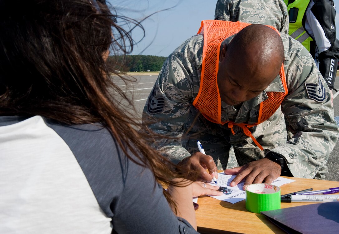 LANGLEY AIR FORCE BASE, Va. -- Airman Stephanie Miller, 633d Security Forces Squadron operations bravo flight member, holds the paper down as Tech. Sgt. Chris Boston, 633d Security Forces Squadron investigator, registers.  The motorcycle ride was part of National Police Week, a celebration in honor of law enforcement officers who lost their lives in the line of duty. (U.S. Air Force photo/Senior Airman Zachary Wolf)
