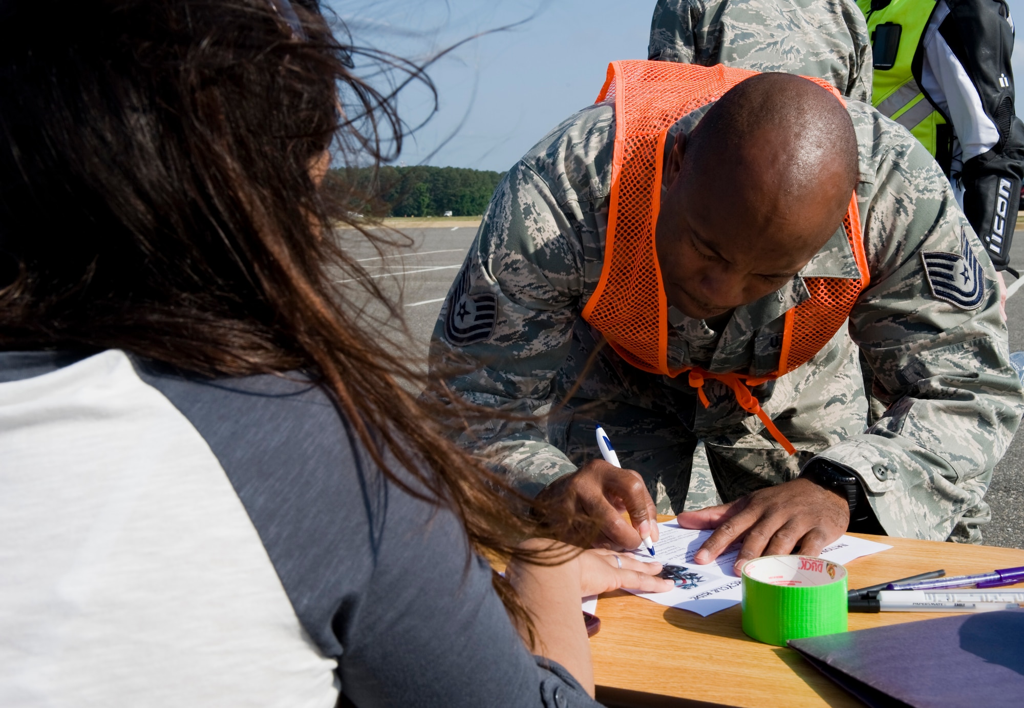 LANGLEY AIR FORCE BASE, Va. -- Airman Stephanie Miller, 633d Security Forces Squadron operations bravo flight member, holds the paper down as Tech. Sgt. Chris Boston, 633d Security Forces Squadron investigator, registers.  The motorcycle ride was part of National Police Week, a celebration in honor of law enforcement officers who lost their lives in the line of duty. (U.S. Air Force photo/Senior Airman Zachary Wolf)