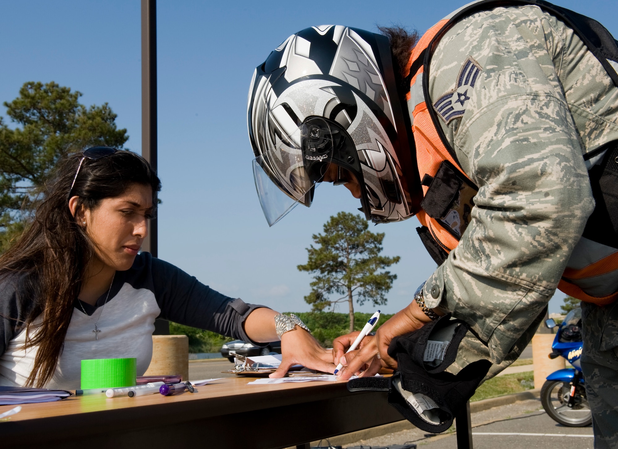 LANGLEY AIR FORCE BASE, Va. -- Airman Stephanie Miller, 633d Security Forces Squadron operations bravo flight member, holds the paper down as Staff Sgt. Adrienne Faircloth, 633d Security Forces Squadron patrolman, registers. The ride was part of National Police Week, a celebration in honor of law enforcement officers who lost their lives in the line of duty. (U.S. Air Force photo/Senior Airman Zachary Wolf)