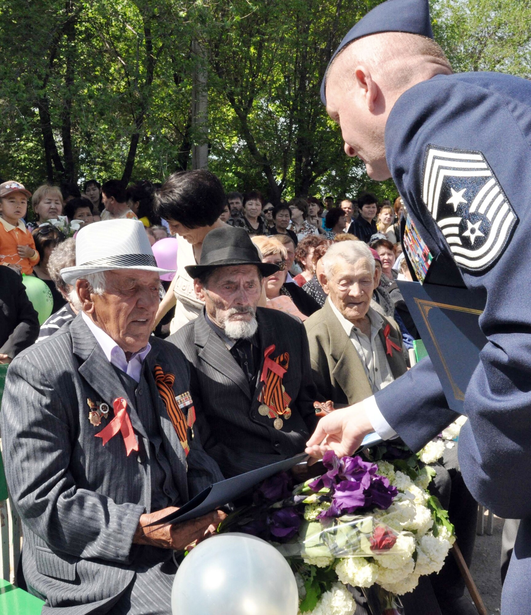 Command Chief Master Sgt. James Dowell presents certificates for the Kyrgyz flag that was flown over Afghanistan during a combat mission to decorated veterans of World War II during a Victory Day celebration May 9, 2010, in Manas Village, Kyrgyzstan. During the event, a memorial wall was unveiled with about 50 names etched in stone of village patriots who died during the war. Chief Dowell is the enlisted leader of the Transit Center at Manas, Kyrgyzstan. (U.S. Air Force photo/Staff Sgt. Carolyn Viss)