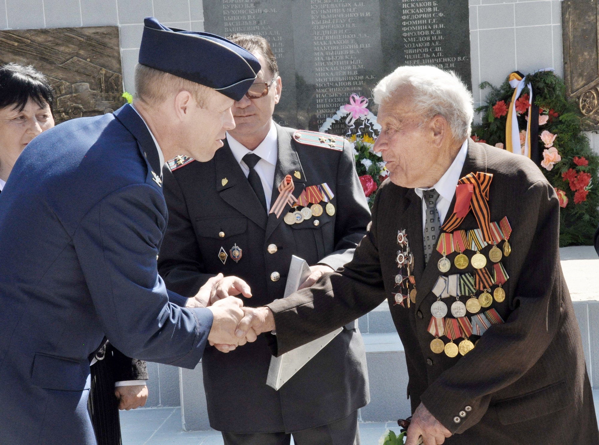 Col. Blaine Holt shakes hands with a highly-decorated veteran of World War II after presenting a Kyrgyz flag to Mr. Beshimbaev Kabylbek, the Mayor of Manas Village, Kyrgyzstan, (center) during a Victory Day ceremony May 9, 2010, in Manas Village, Kyrgyzstan. Colonel Holt is the director of the Transit Center at Manas. (U.S. Air Force photo/Staff Sgt. Carolyn Viss)