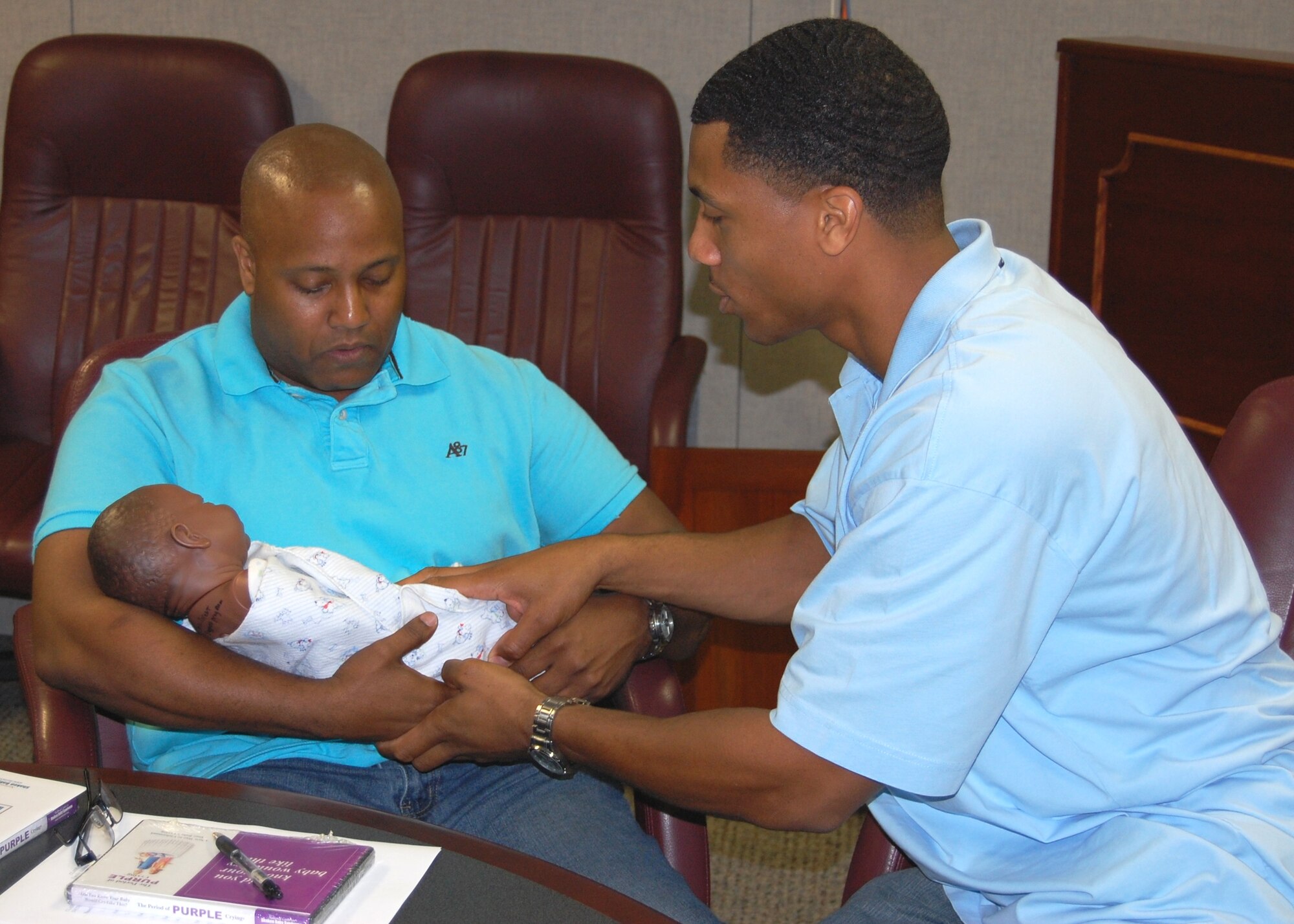 Master Sgt, Kendal Dismute, right, 336th Training Squadron first sergeant and a father himself, explains to Sean Fornéy, 81st Surgical Operations Squadron, how to hold a swaddled infant during the “Dad’s 101:  A Class for Dads, by Dads” Friday at the Arnold Annex.  The class, hosted by Keesler’s family advocacy program, gives expectant or new dads an opportunity to practice baby ‘basics’ such as diapering, feeding and bathing as well as discuss concerns, issues, fears or expectations about fatherhood.  Mr. Fornéy and his wife Milvia are expecting their first child — a boy — June 4.   (U.S. Air Force photo by Steve Pivnick)
